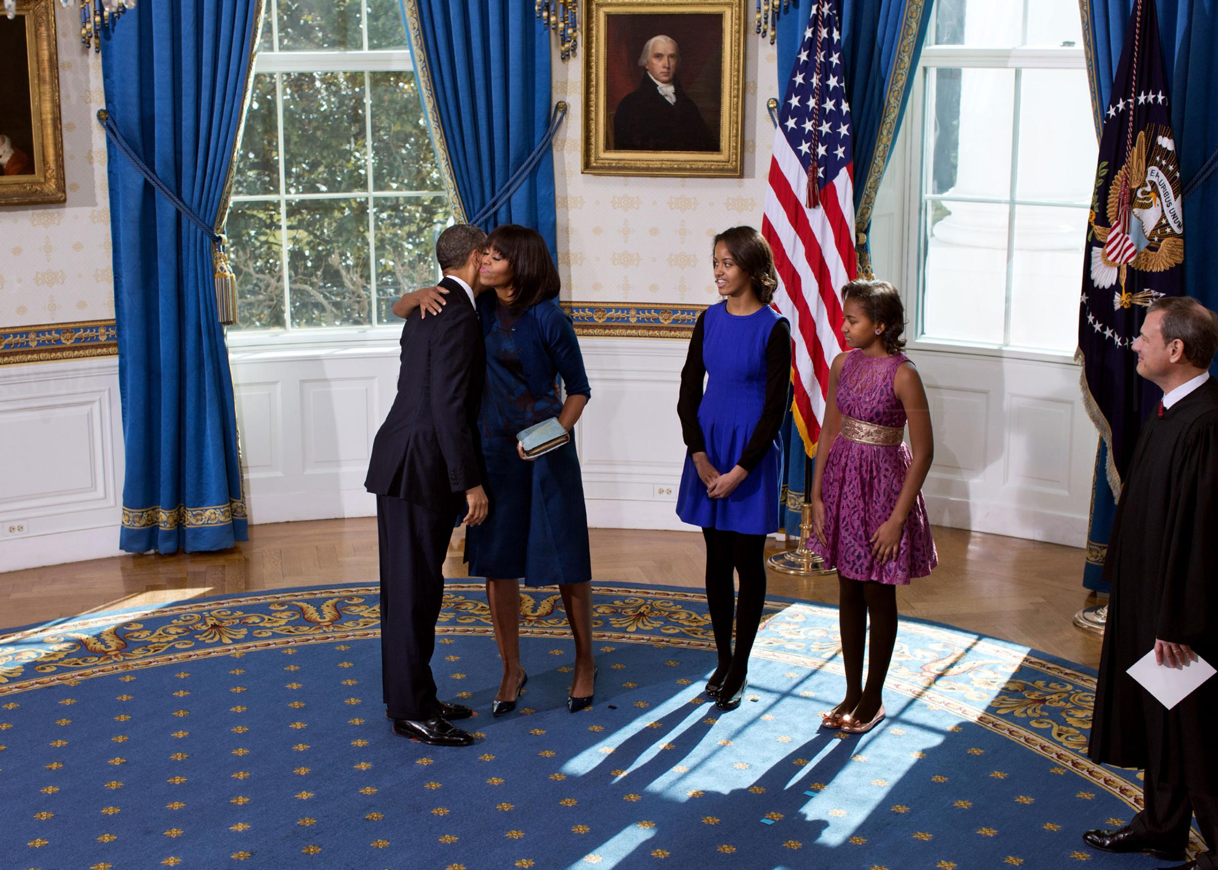 President Barack Obama and First Lady Michelle Obama embrace following the official swearing-in ceremony in the Blue Room of the White House on Inauguration Day, Sunday, Jan. 20, 2013. Standing, from left, are daughters Sasha and Malia and Supreme Court Chief Justice John G. Roberts, Jr.