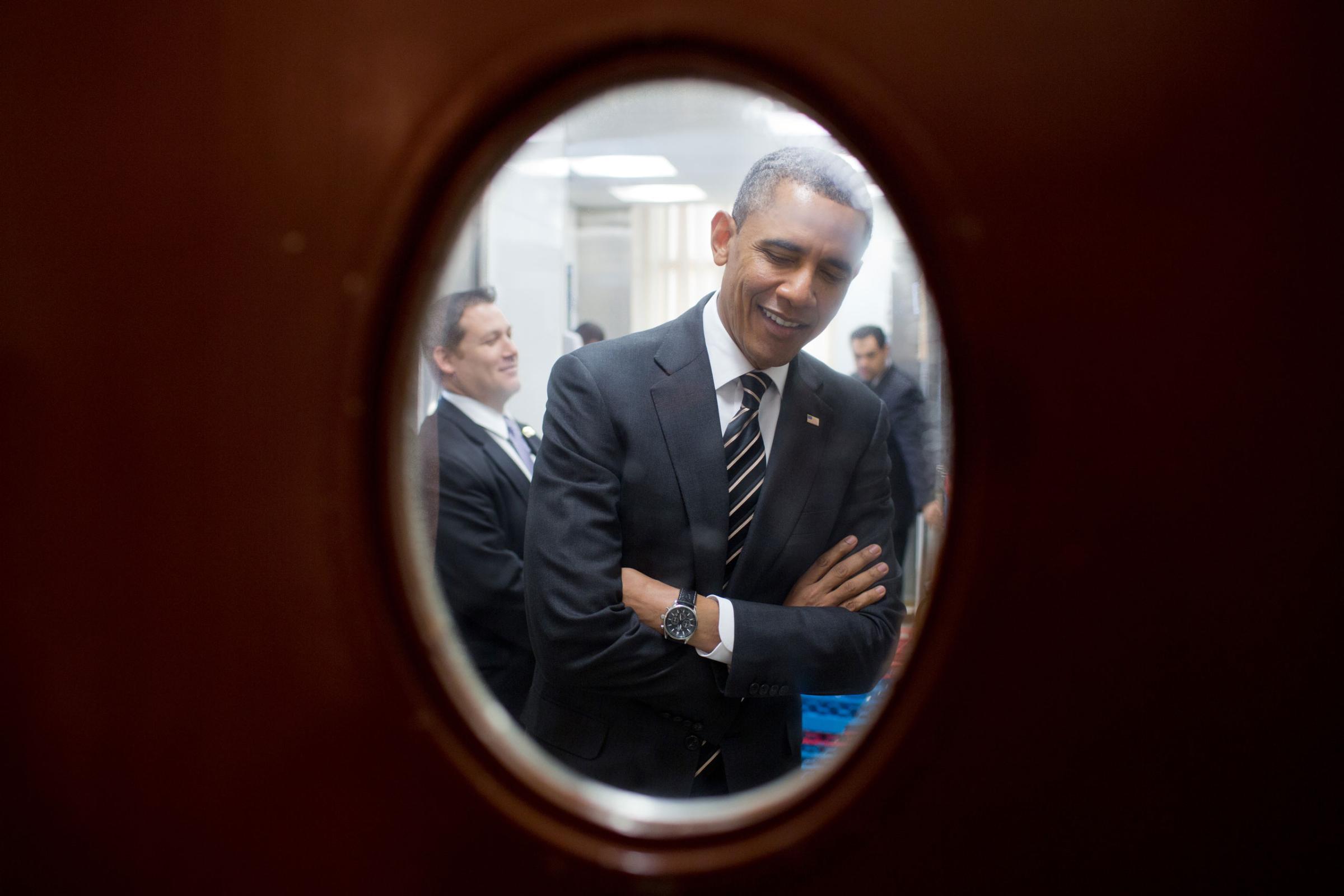 President Barack Obama is seen through a door to the pantry near the State Dining Room of the White House as he waits to meet with the National Governors Association, Feb. 25, 2013.
