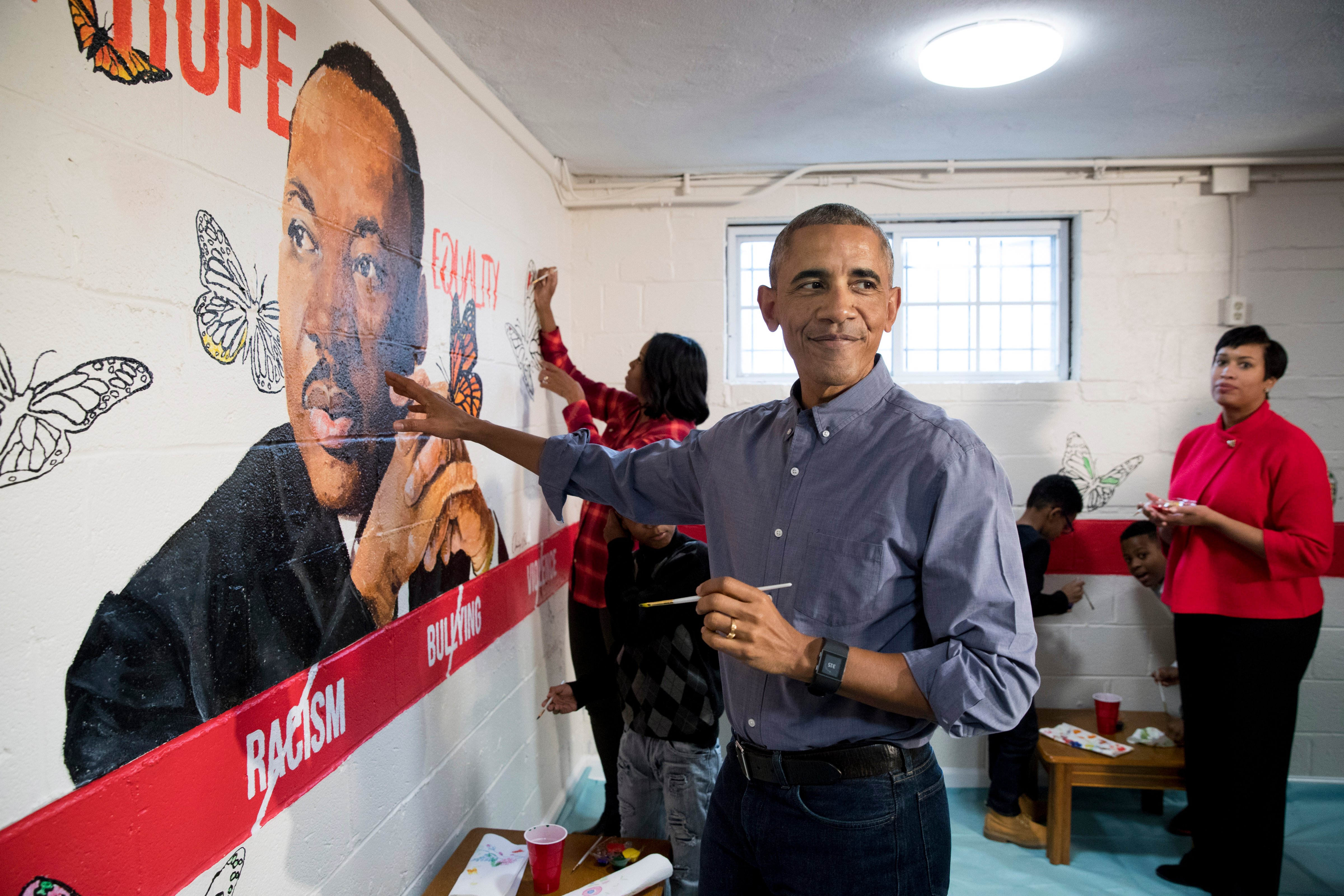 WASHINGTON, DC - JANUARY 16: (AFP OUT) U.S. President Barack Obama (Front) and First Lady Michelle Obama (Back) help paint a mural depicting Martin Luther King Jr., as Mayor of Washington DC Muriel Bowser (R) looks on, at the Jobs Have Priority Naylor Road Family ShelterJanuary 16, 2017 in Washington, DC. President Obama and the First Lady attended a service event at the Jobs Have Priority Naylor Road Family Shelter for Martin Luther King Jr. Day. (Photo by MICHAEL REYNOLDS-Pool/Getty Images) (Pool—Getty Images)