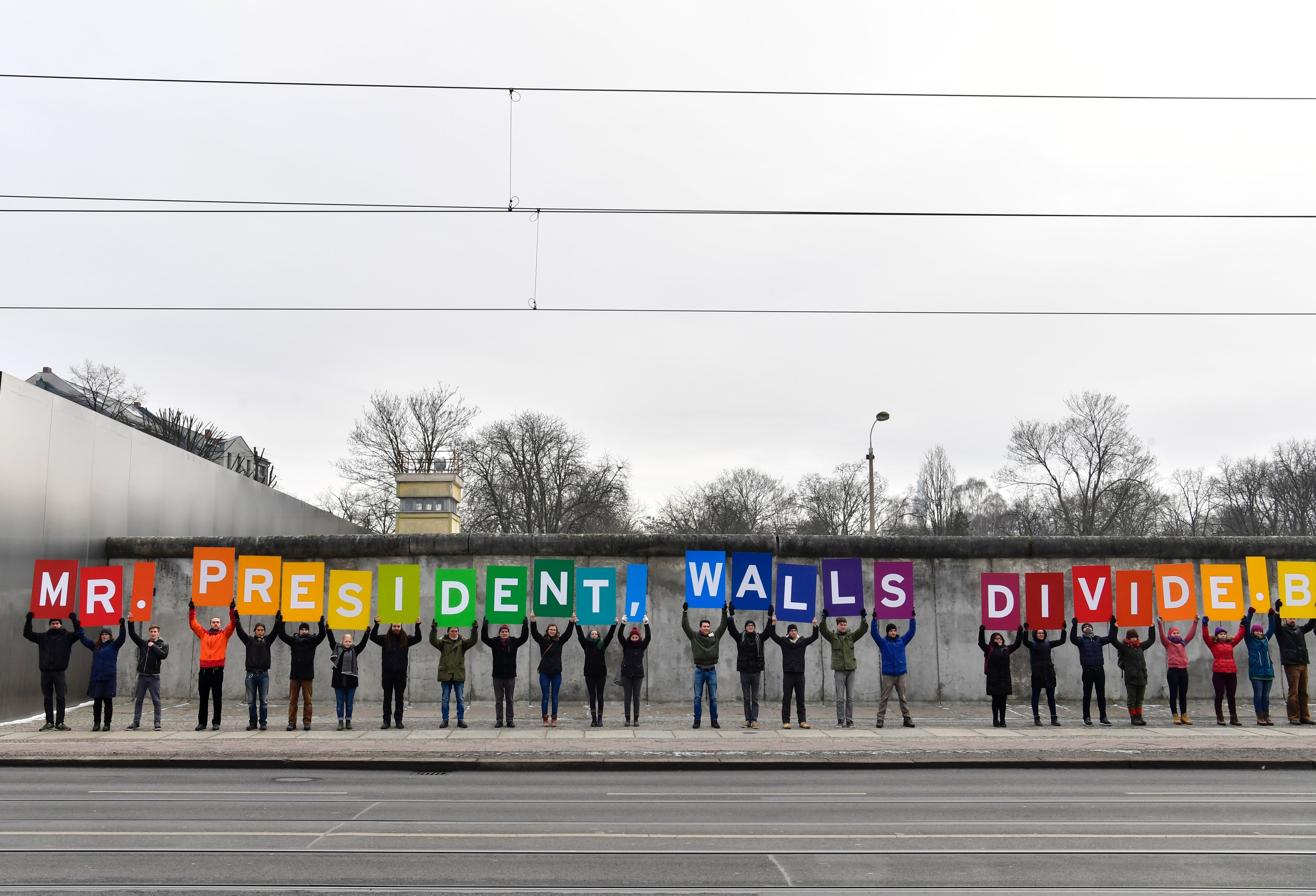 Activists from Greenpeace display a message reading "Mr. President, walls divide. Build Bridges!" along the Berlin wall in Berlin on Jan. 20, 2017 to coincide with the inauguration of U.S. President Donald Trump. (John MacDougall—AFP/Getty Images)