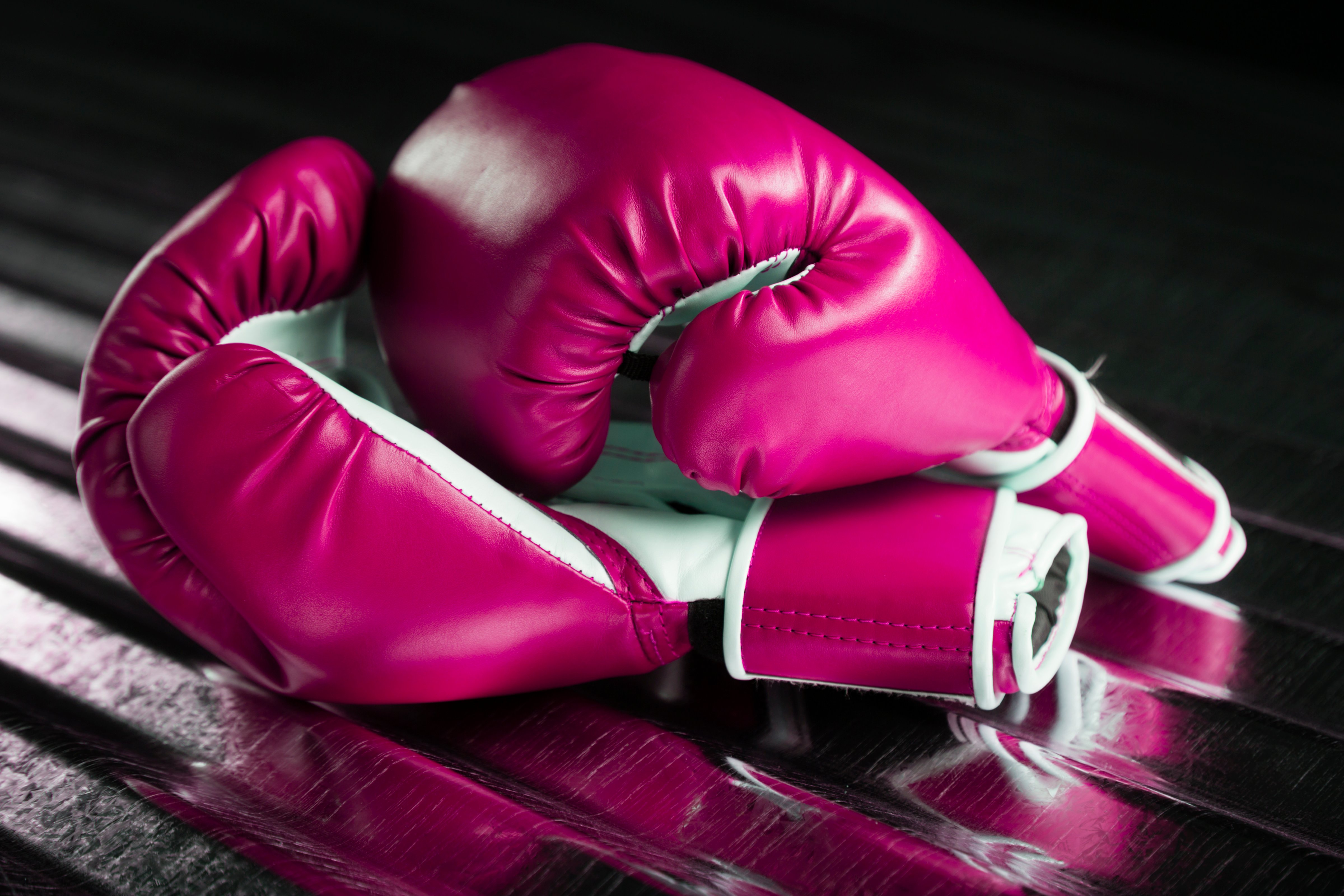 A pair of pink boxing gloves on a metallic background. (RichLegg—Getty Images/iStockphoto)