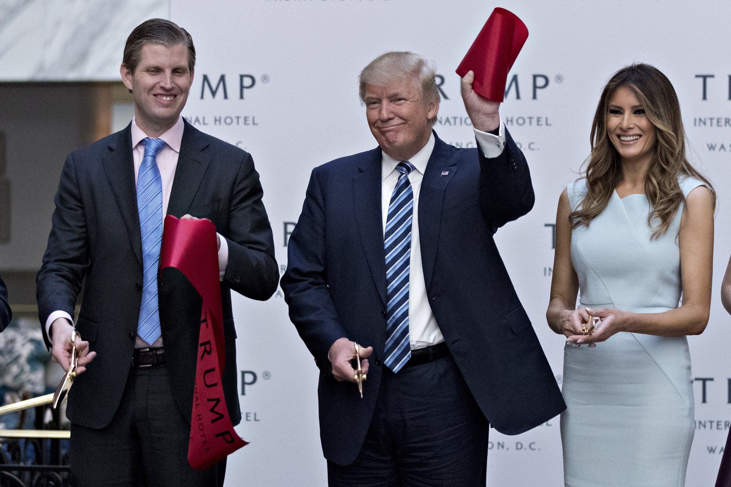 Donald Trump holds a piece of ribbon next to his wife Melania Trump, right, and his son Eric Trump during the grand opening ceremony of the Trump International Hotel in Washington, D.C., U.S., on Wednesday, Oct. 26, 2016.