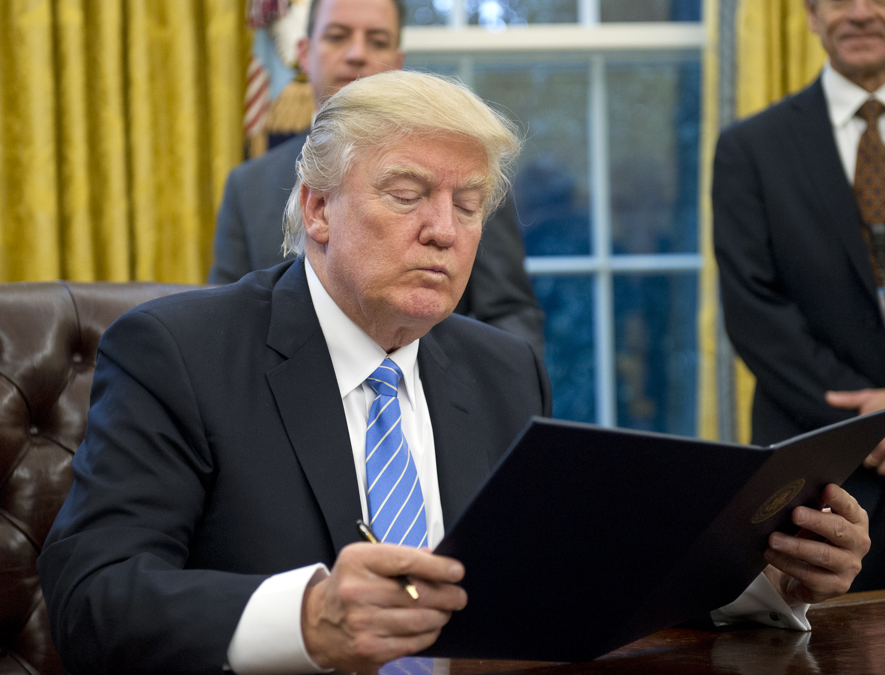 WASHINGTON, DC - JAN. 23: (AFP OUT) U.S. President Donald Trump reads the first of three Executive Orders he will sign in the Oval Office of the White House in Washington, DC on Monday, January 23, 2017.  This one concerned the withdrawal of the United States from the Trans-Pacific Partnership (TPP).  The others will be a US Government hiring freeze for all departments but the military, and "Mexico City" which bans federal funding of abortions overseas. (Pool—Getty Images)