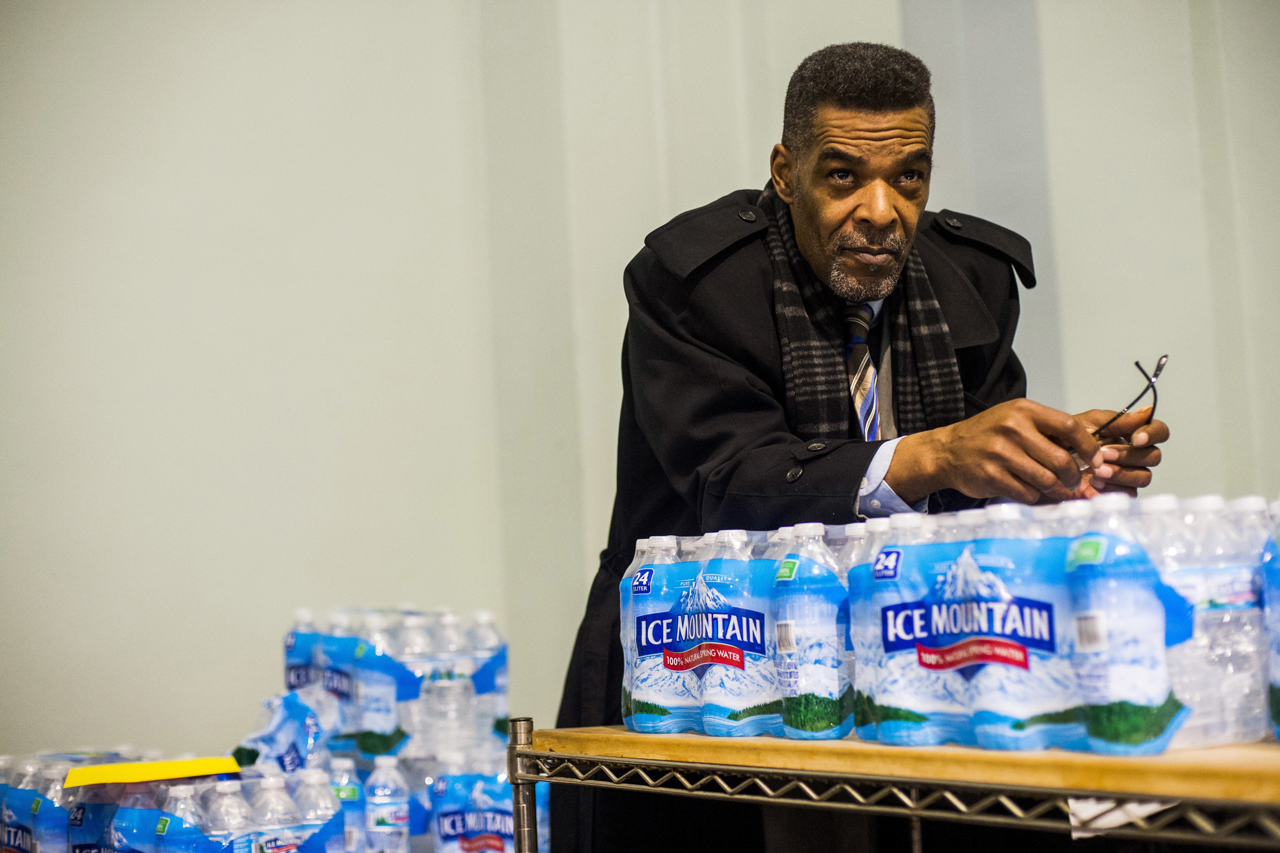 Flint City Councilman Eric Mays leans on a palette of water as he listens to health officials answer residents' questions during a Flint water town hall meeting at the University of Michigan-Flint Northbank Center in Flint, Mich., on Jan 12, 2017. (Jake May—AP)