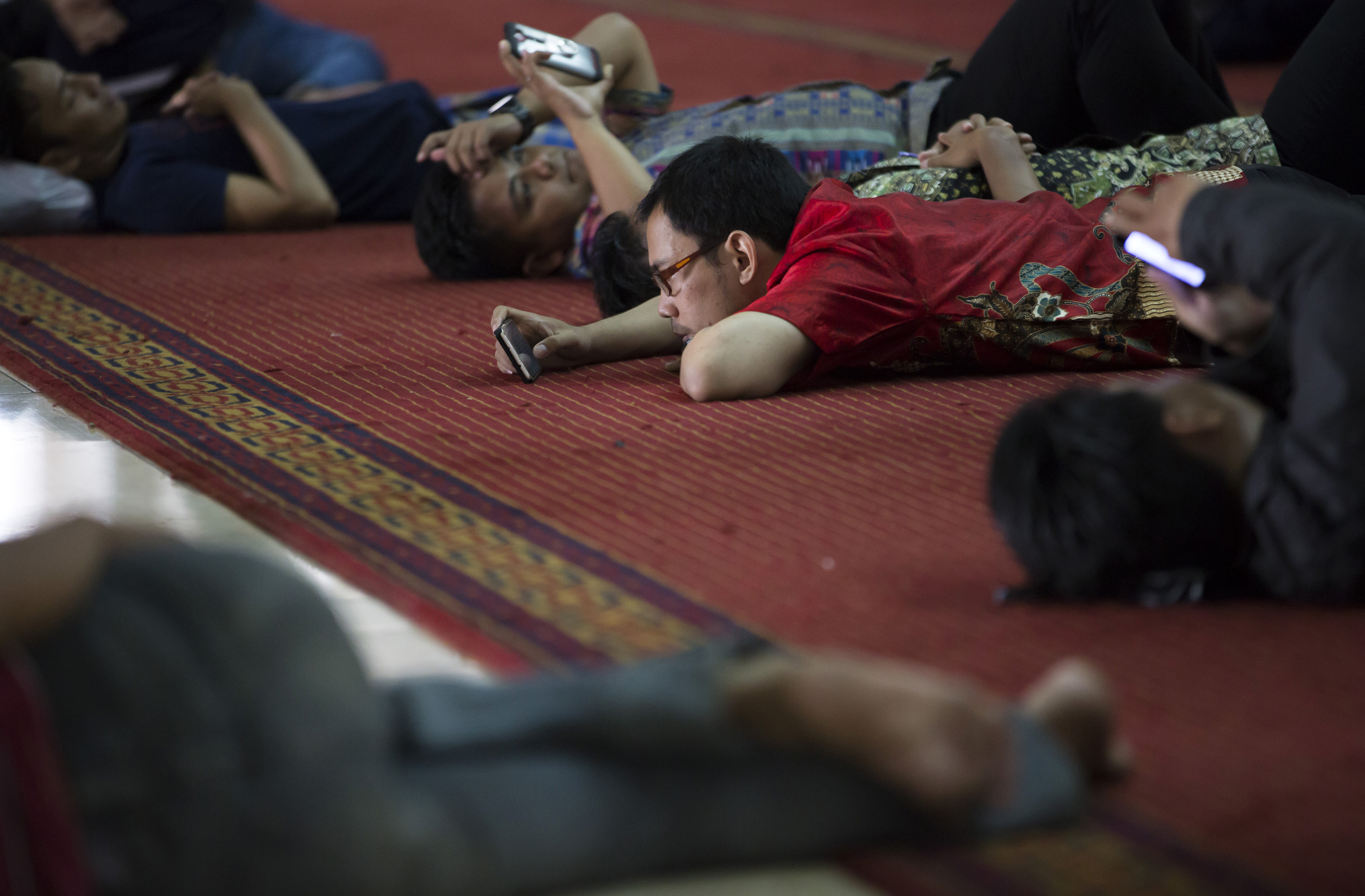 Muslims use smartphones as they rest after attending Friday prayers at the Istiqlal Mosque on Sept. 30, 2016, in Jakarta (Tomohiro Ohsumi—Getty Images)