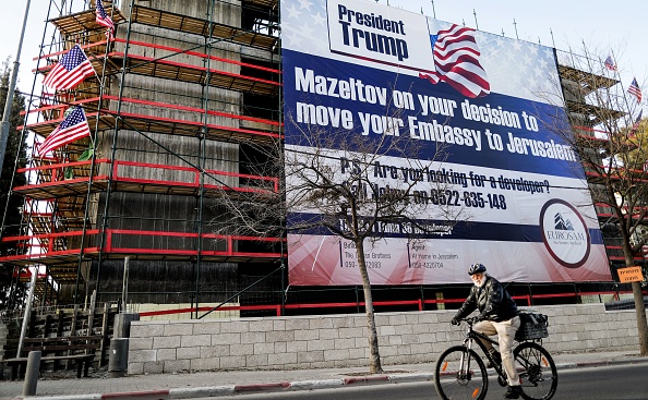 A man cycles past a giant banner, bearing a message of congratulations (Mazeltov) for incoming US President Donald Trump, covering a building under construction in central Jerusalem on January 20, 2017.
