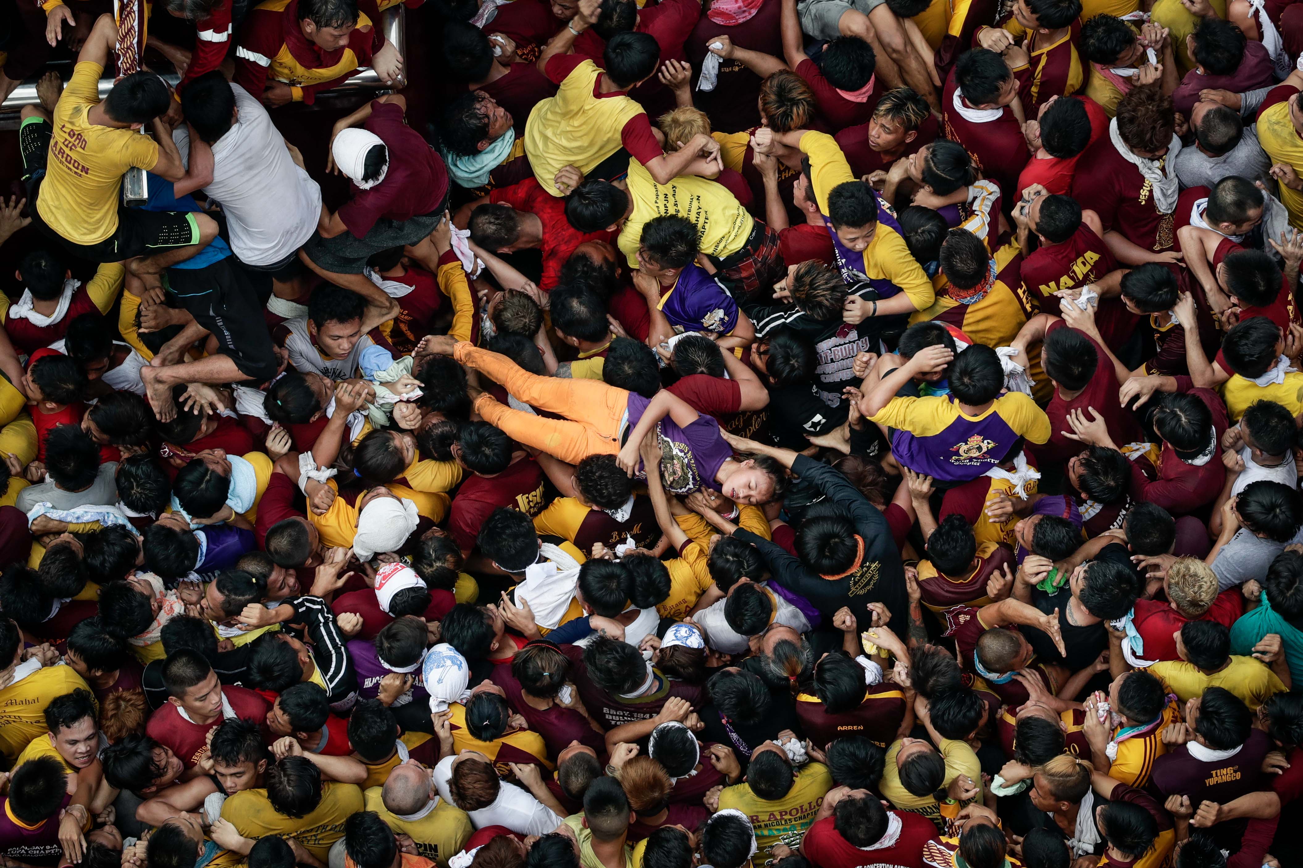 A woman is carried off by a crowd of devotees near the statue of the Black Nazarene during the procession at the Jones Bridge in Manila on Jan. 9, 2017 (Mark R. Cristino—EPA)
