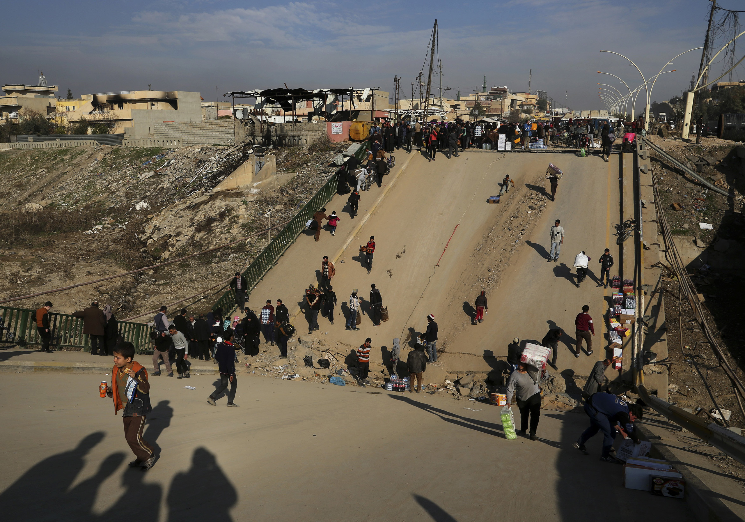 People cross a bridge destroyed by Islamic State militants in a neighbourhood recently liberated from Islamic State on the eastern side of Mosul, Iraq on Jan. 18, 2017. (Khalid Mohammed—AP)