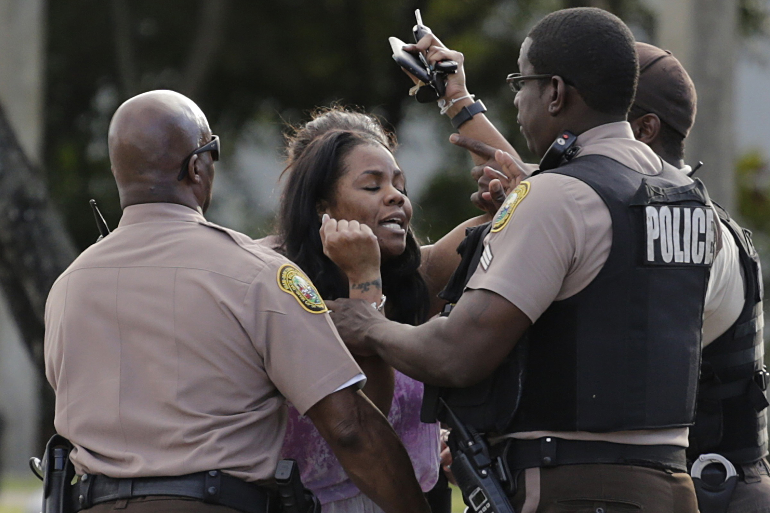 A concerned mother is met by Miami-Dade police officers as she searches for her child after several were injured in a shooting at Martin Luther King Jr. Memorial Park in Miami-Dade, Fla., on, Jan. 16, 2017. (Carl Juste—Miami Herald/AP)
