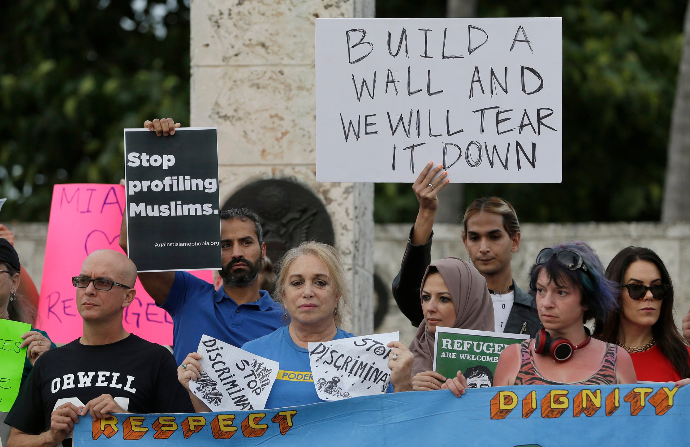 Protesters hold signs during a rally against President Donald Trump's executive order on immigration in downtown Miami. on Jan. 26, 2017.