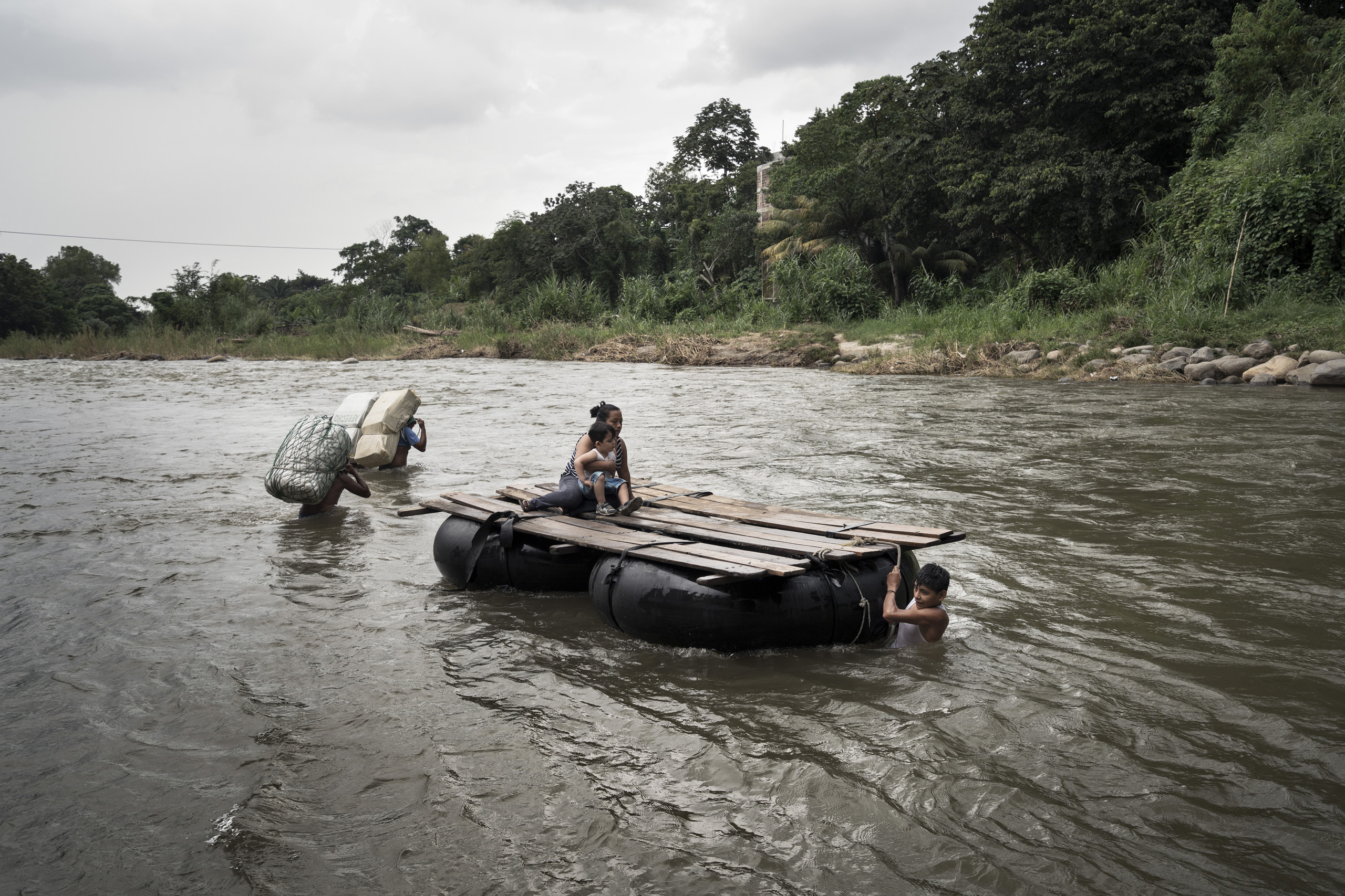 In the surrounding of the town of Talismàn, two smugglers and a mother with her son are illegally crossing the Rio Suchiate. The smugglers are going to Mexico while the mother with her son are going back to Guatemala, it is normal here to cross the border only to go shopping in Mexico. Guatemala. Sept. 21, 2016.