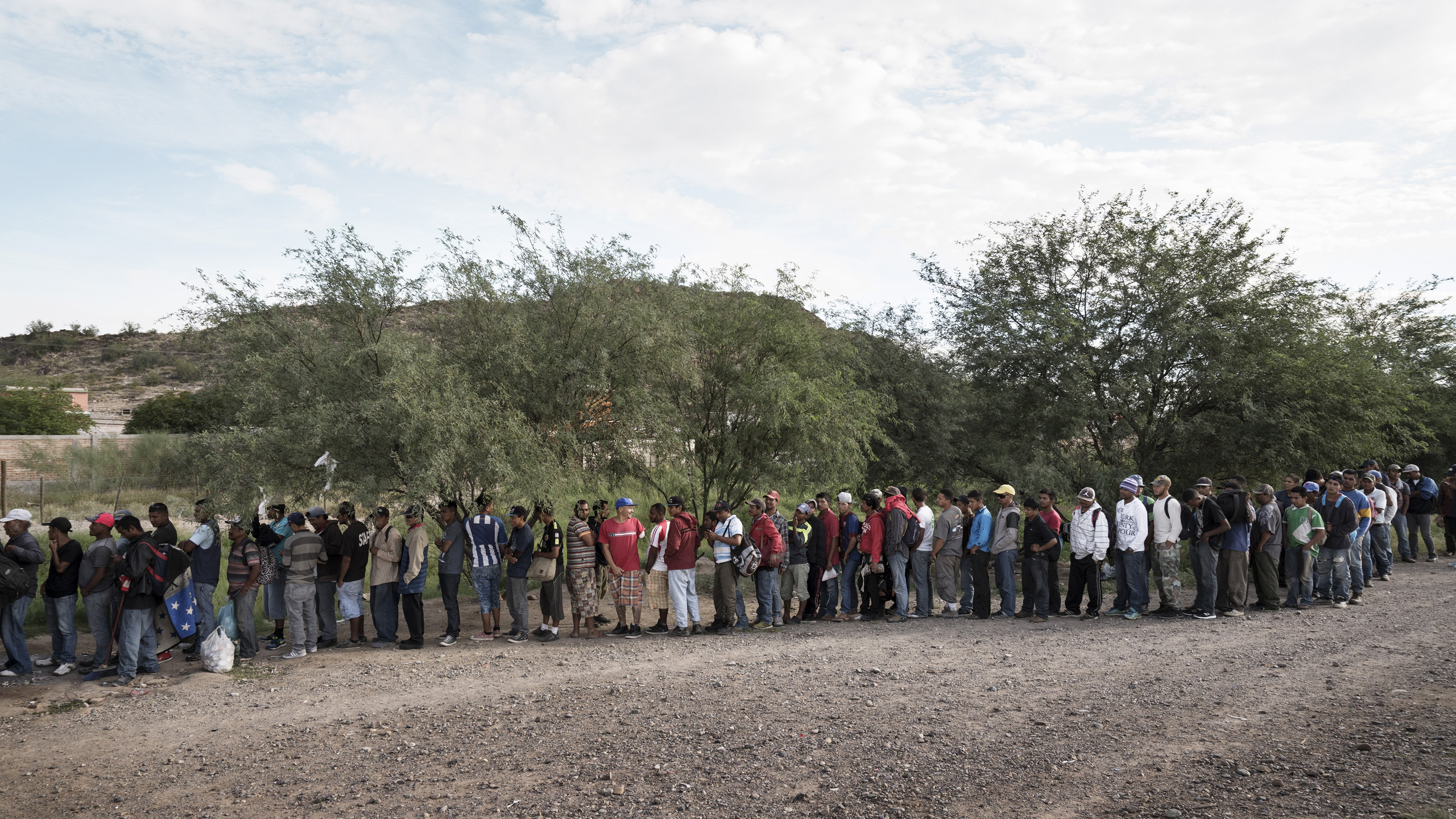 Illegal Central American and Mexican migrants wait in line for a hot meal delivered every morning by a group of volunteers from the city of Caborca. Caborca, Sonora, Mexico. Oct. 6, 2016.