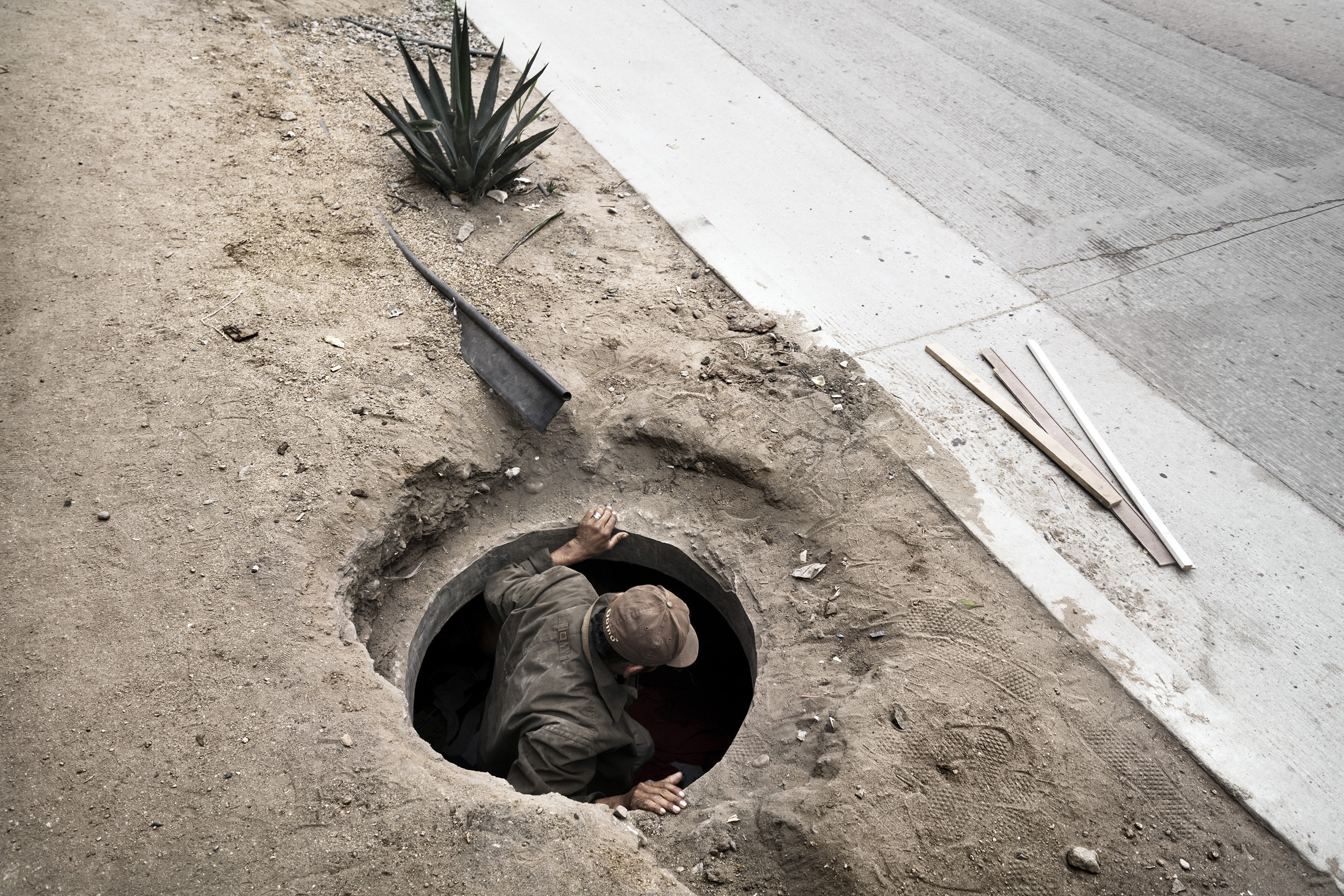 An illegal Central American migrant comes out of a manhole where he lives, along the road that flanks the border between Mexico and the U.S. He is waiting for the right moment to cross the border.Tijuana, Baja California, Mexico. Oct. 12, 2016.