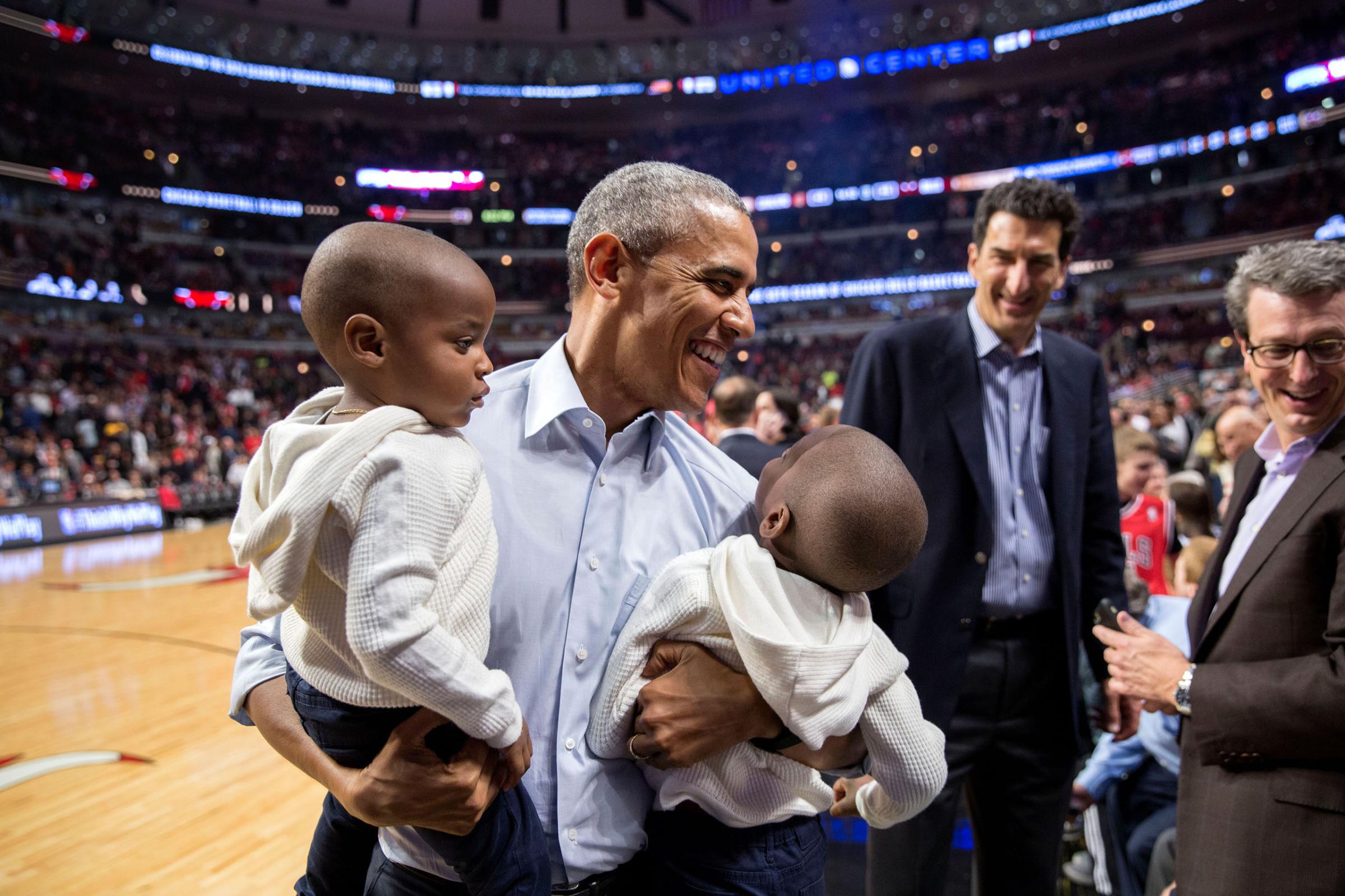 President Barack Obama holds two youngsters while posing for a photo with them during halftime of the Chicago Bulls-Cleveland Cavaliers basketball game at the United Center in Chicago, Ill., Oct. 27, 2015. (Official White House Photo by Pete Souza)This official White House photograph is being made available only for publication by news organizations and/or for personal use printing by the subject(s) of the photograph. The photograph may not be manipulated in any way and may not be used in commercial or political materials, advertisements, emails, products, promotions that in any way suggests approval or endorsement of the President, the First Family, or the White House.
