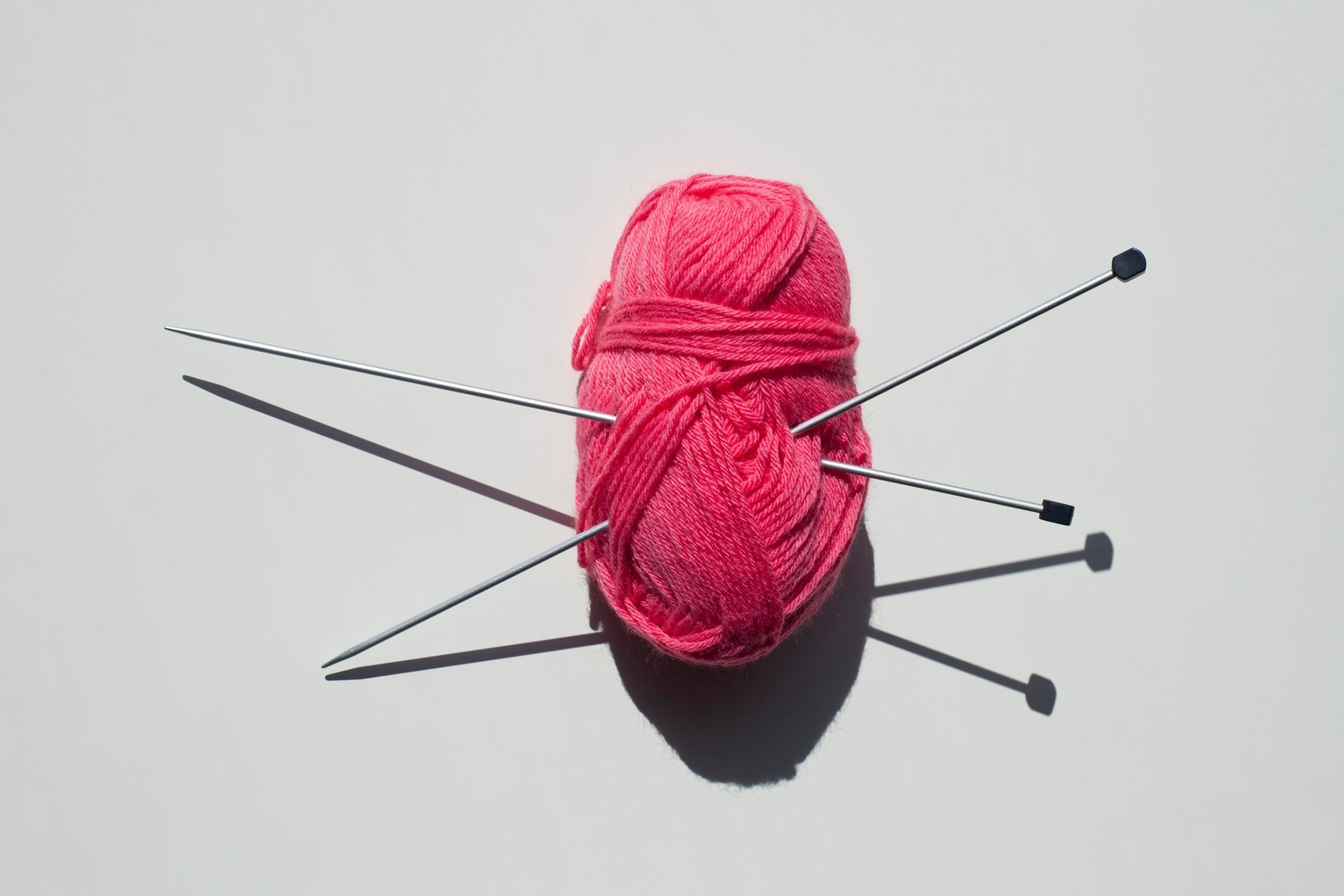 A pair of knitting needles stuck into a ball of yarn