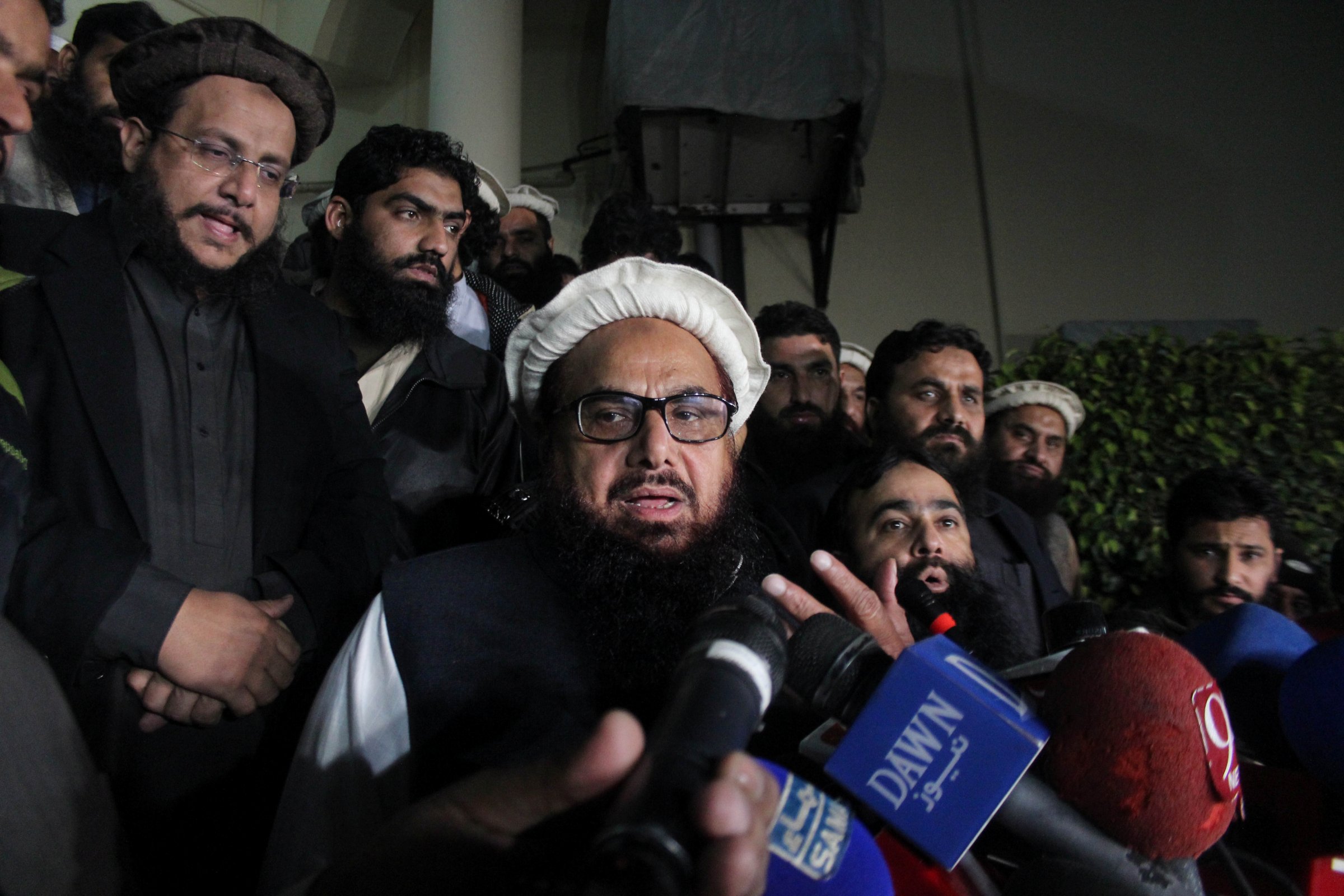 Hafiz Muhammad Saeed, chief of the banned Islamic charity Jamat-ud-Dawa, speaks with media as he is escorted to his home where he will be under house arrest in Lahore