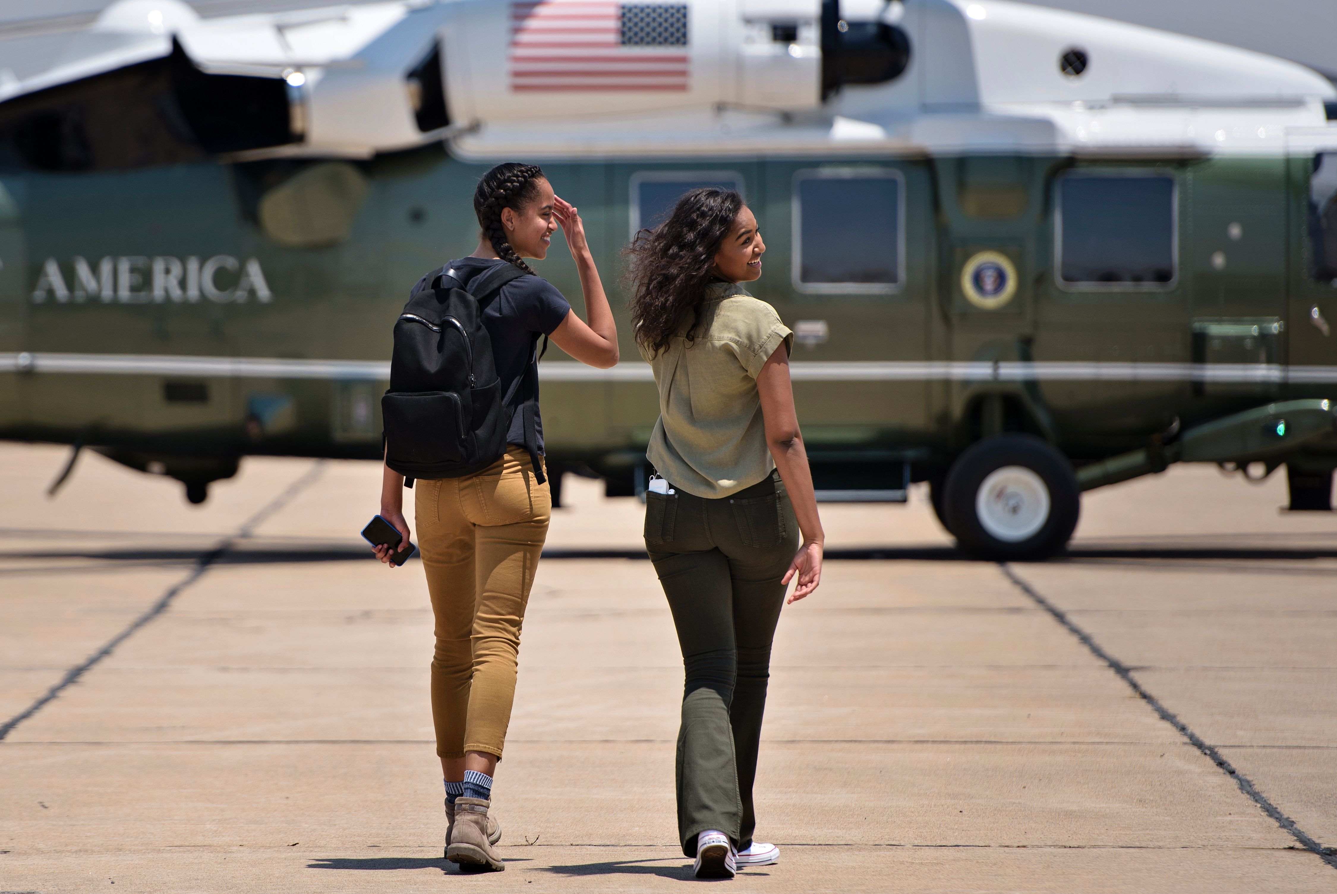 Malia and Sasha walk to a helicopter while looking back at their parents at Roswell International Air Center in Roswell, New Mexico, on June 17, 2016.