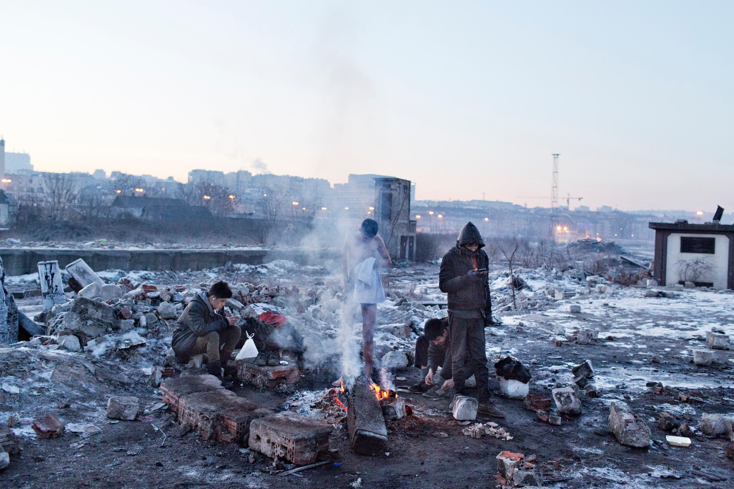 A group of unaccompanied minors form afghanistan , include a boy with disability, to keeps warm by starting a makeshift fire near the train station of Belgrade, Jan 15, 2017.