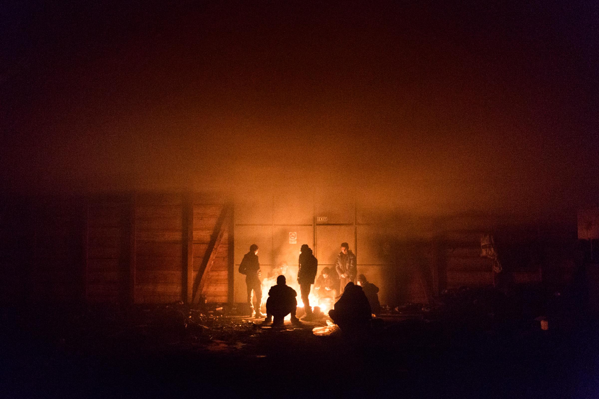 A group of unhacampaniend minors from Afghanistan tries to keep warm by starting a makeshift fire in abandoned warehouse in Belgrade, Jan. 14, 2017