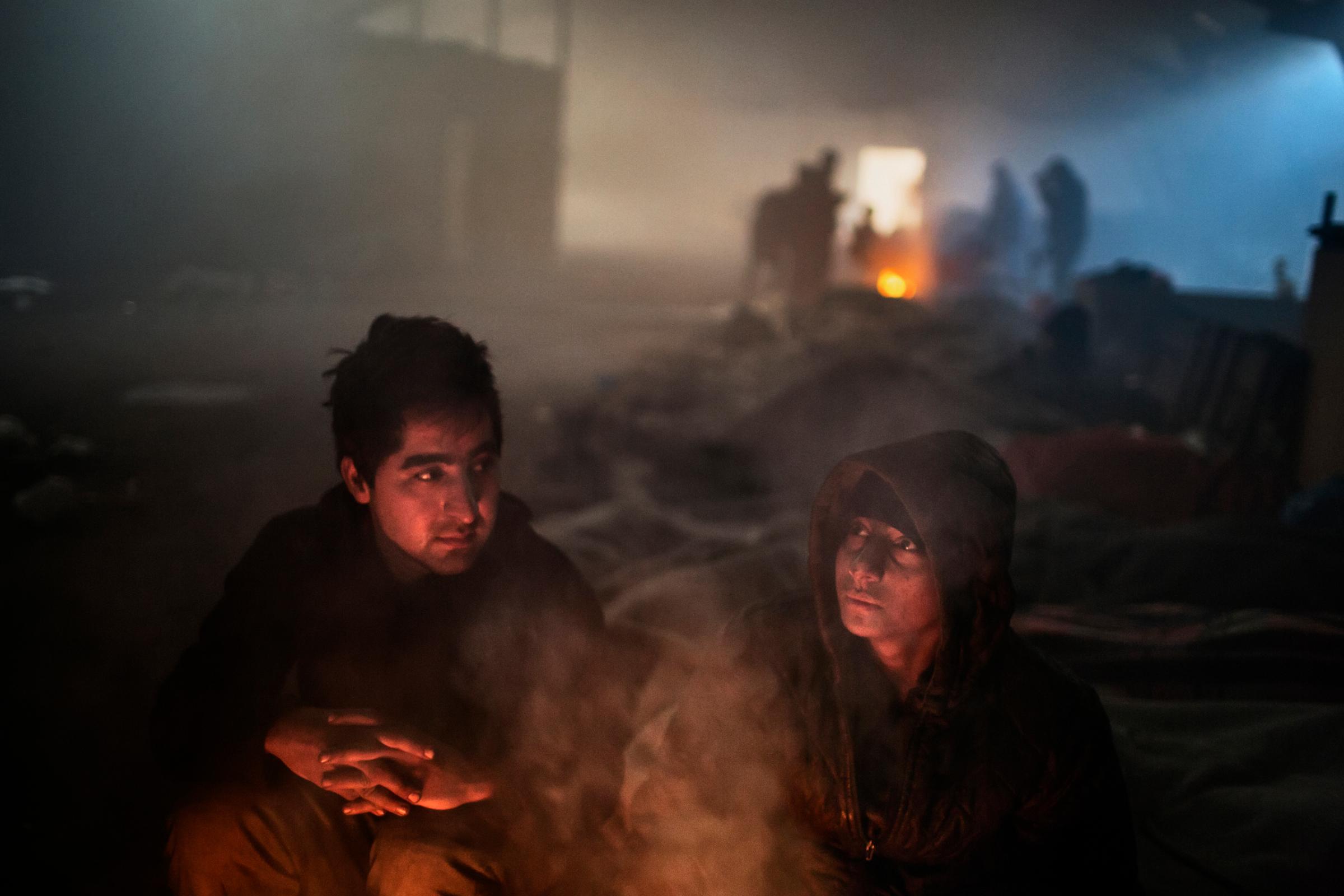 Two unaccompanied minors from afghanistan stay warm inside an abandoned warehouse in Belgrade, Jan 13, 2017