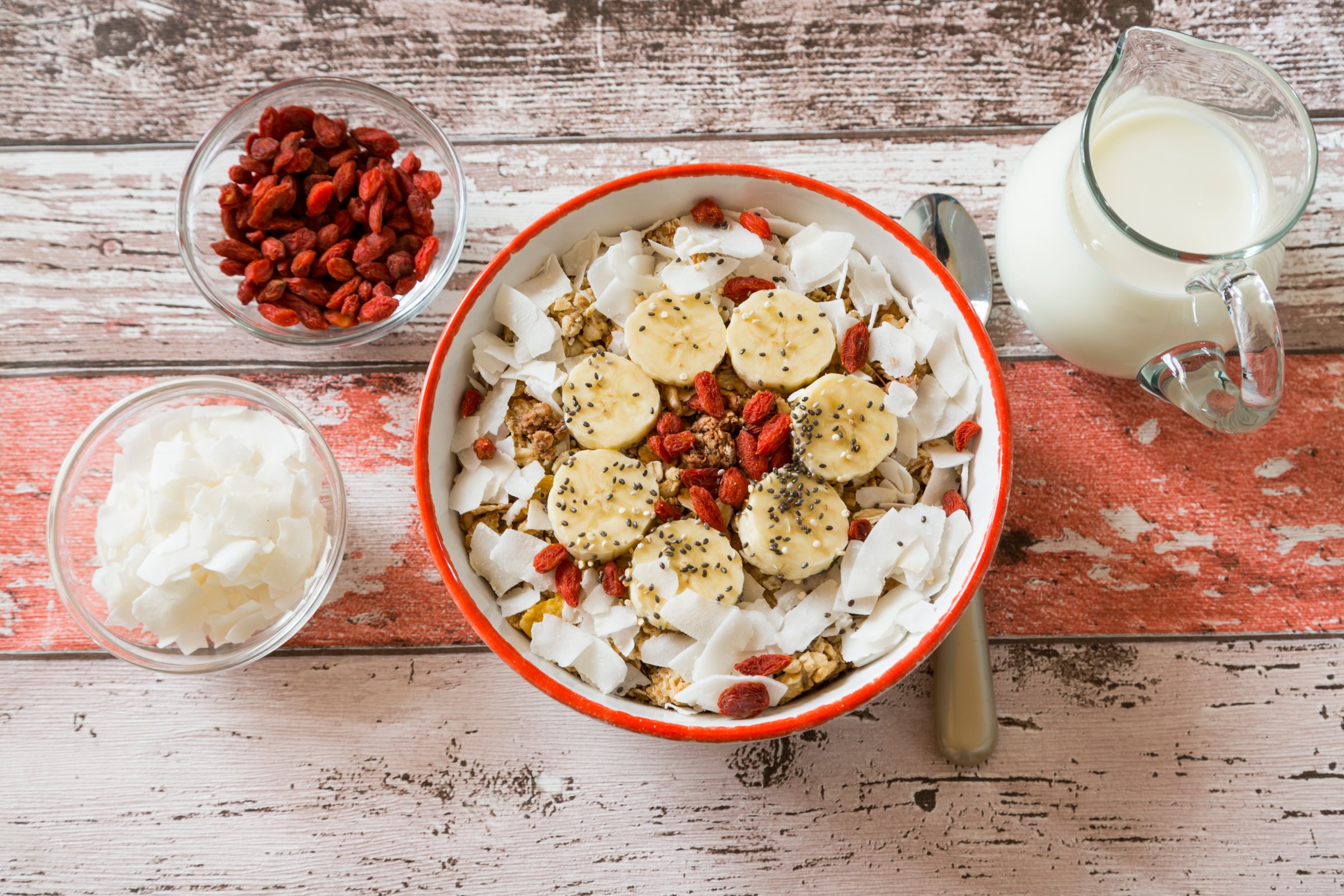 Bowl of muesli with banana slices, chia seeds, coconut chips and goji berries