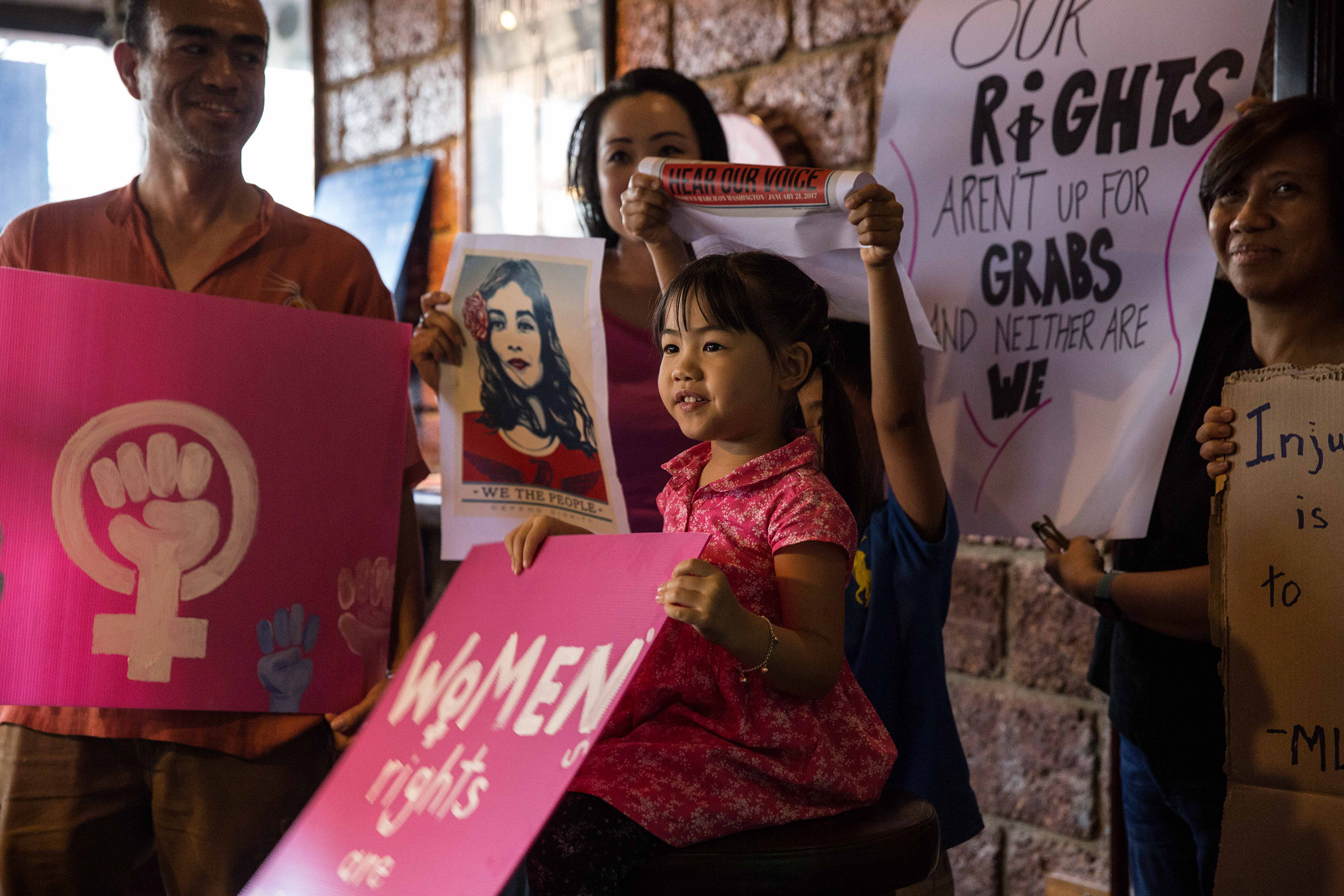 A young Thai girl holds a  women's rights are human rights  sign at Roadhouse BBQ restaurant where many of the Bangkok Women's March participants gathered on Jan. 21, 2017 in Bangkok, Thailand.