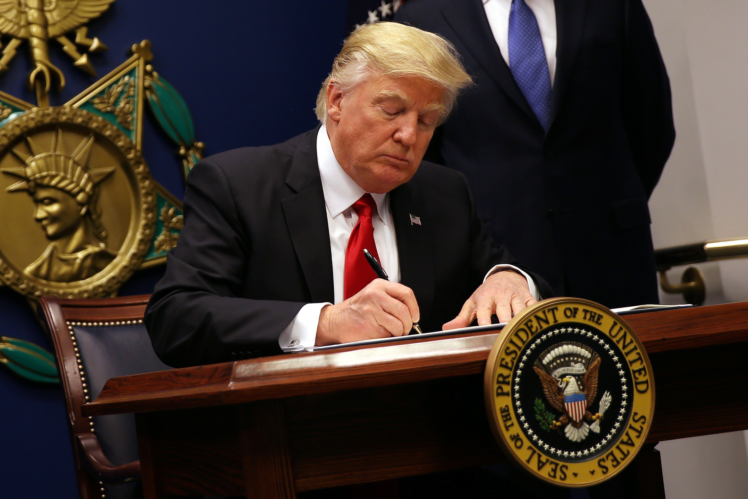 President Donald Trump signs an executive order imposing a four-month travel ban on refugees entering the United States and a 90-day hold on travelers from Syria, Iran and five other Muslim-majority countries at the Pentagon in Washington on Jan. 27, 2017. (Carlos Barria—Reuters)