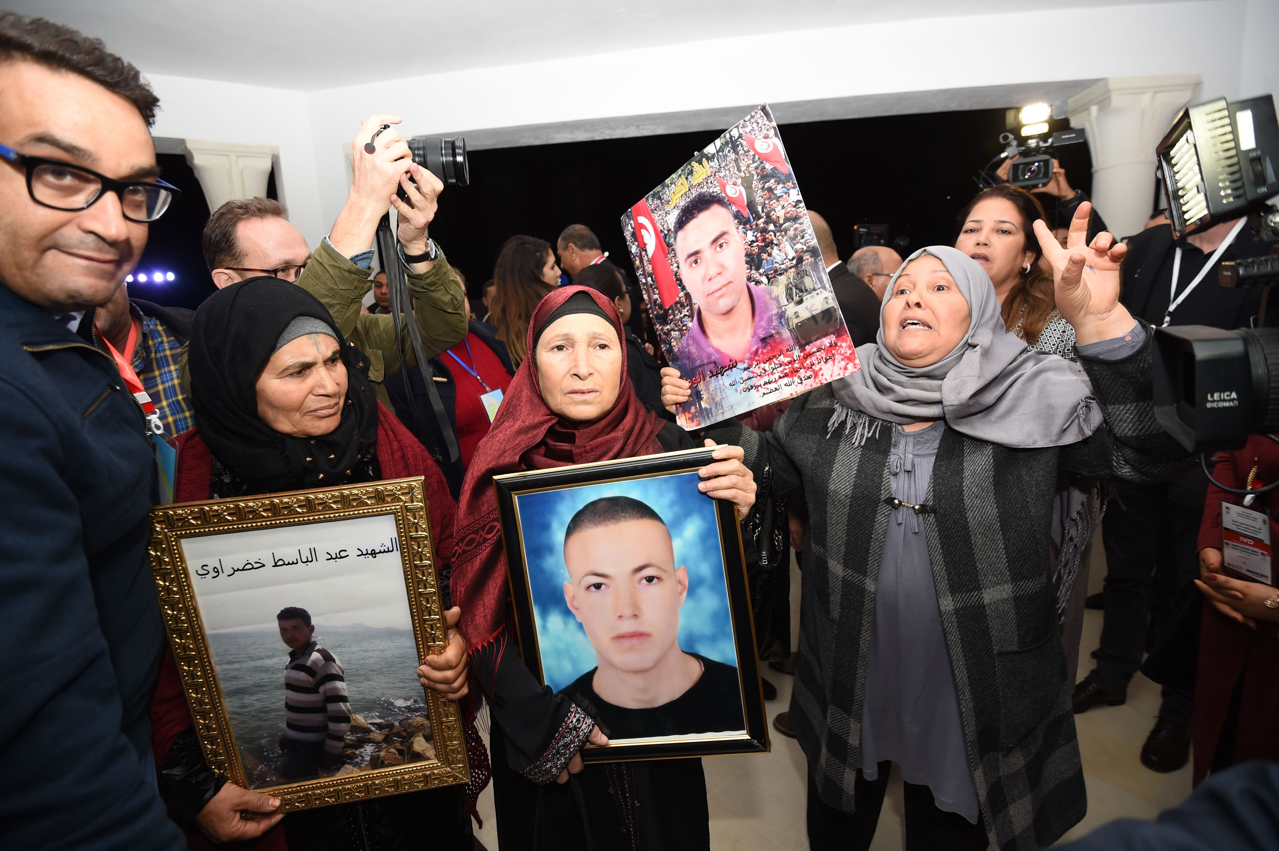 Tunisian mothers of a torture victims carry their sons' portraits as they arrive for a hearing before the The Truth and Dignity Commission (IVD) in Tunis on Nov. 17, 2016. (Fethi Belaid—AFP/Getty Images)
