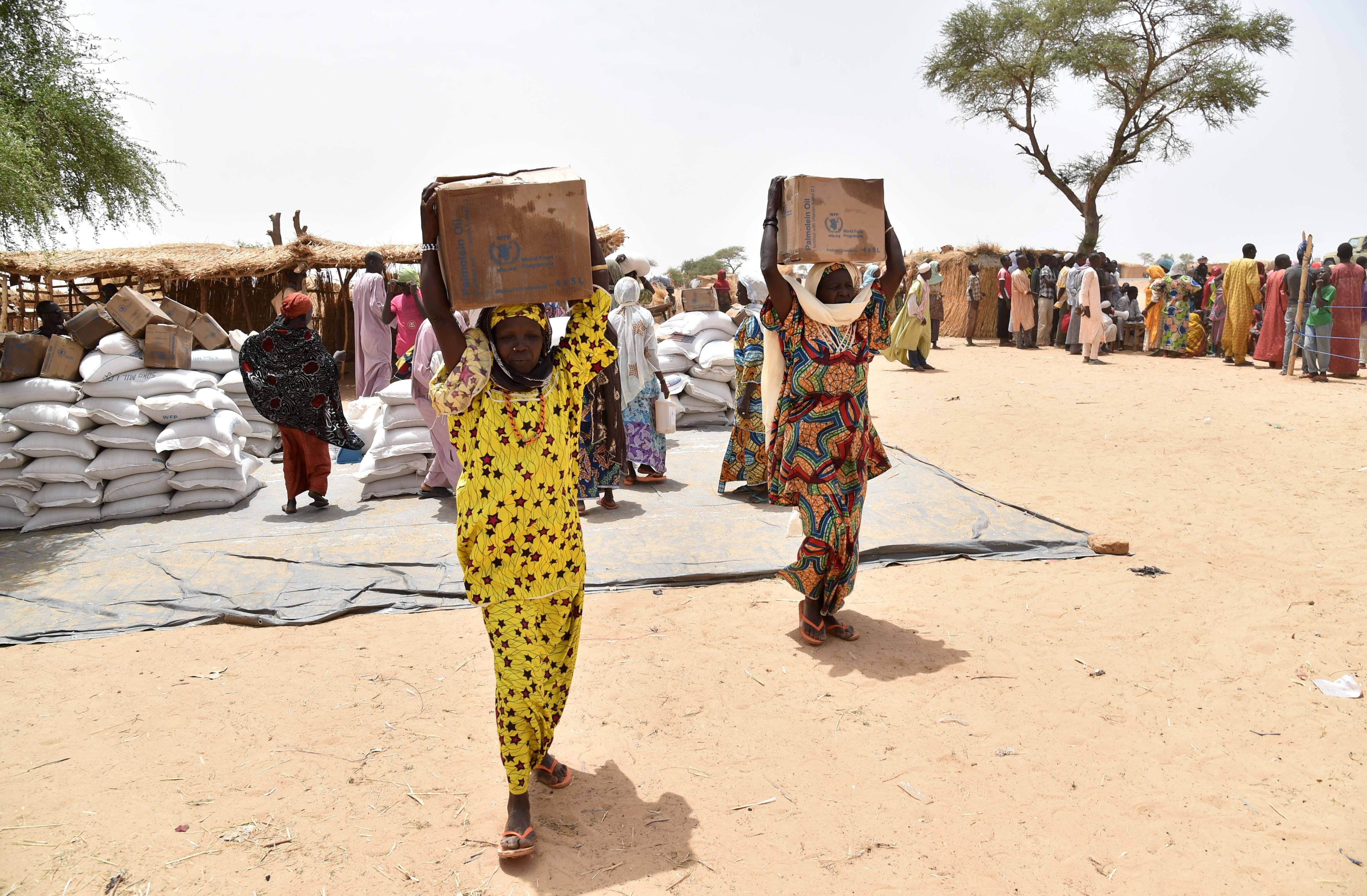 Displaced people fleeing from Boko Haram incursions into Niger carry boxes of oil during a World Food Programme (WFP) and USAID food distribution at the Asanga refugee camp near Diffa on June 16, 2016. (Issouf Sanogo—AFP/Getty Images)