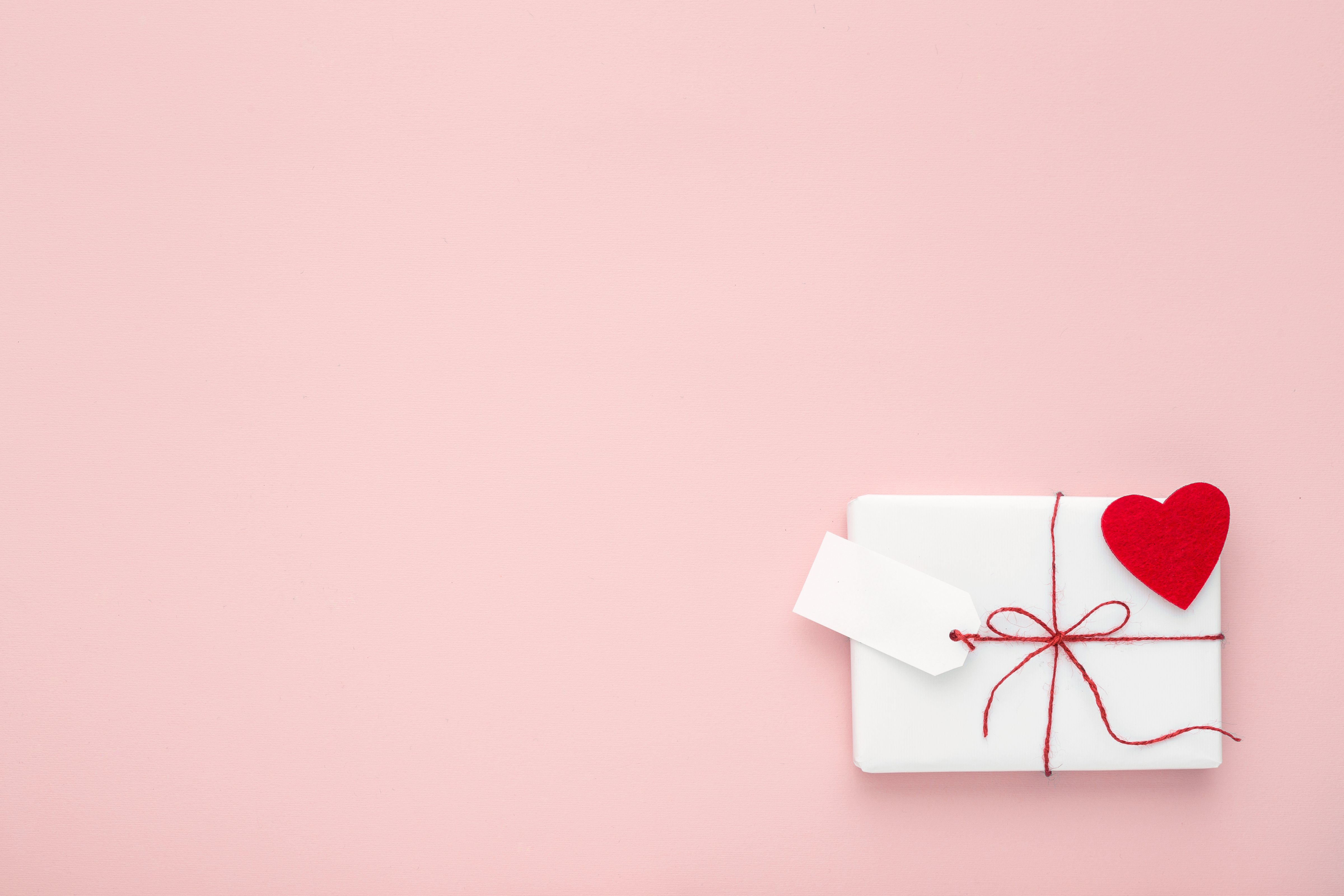 Valentine or birthday white gift with red bow,  blank label decorated with felt heart on pink background. Flat lay. Copy space. (mallmo—Getty Images/iStockphoto)