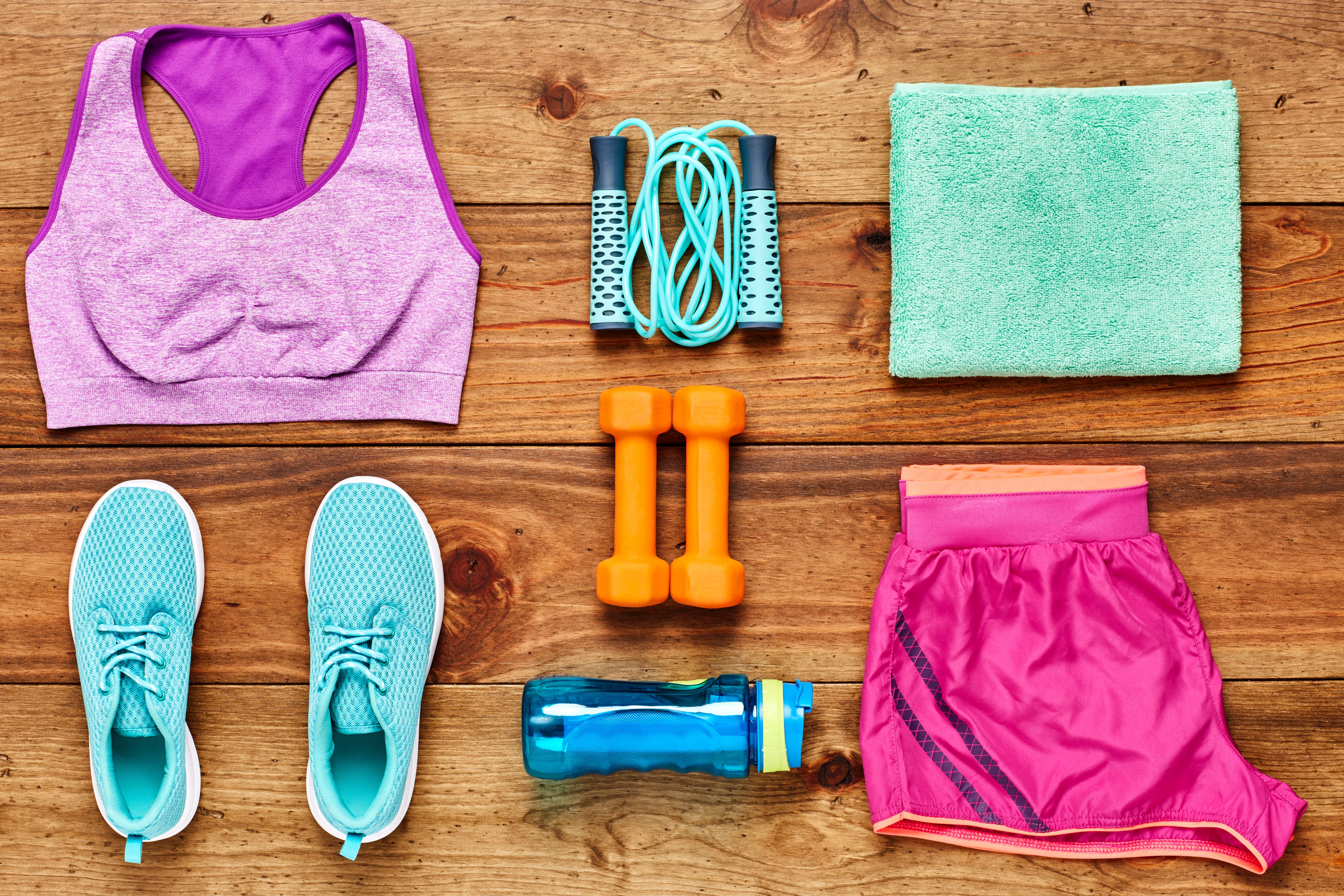 Directly above flat lay shot of sports equipment arranged on hardwood floor. Dumbbells are surrounded with sports clothing  water bottle  towel and shoes on wood. All are representing healthy lifestyle. (Getty Images)
