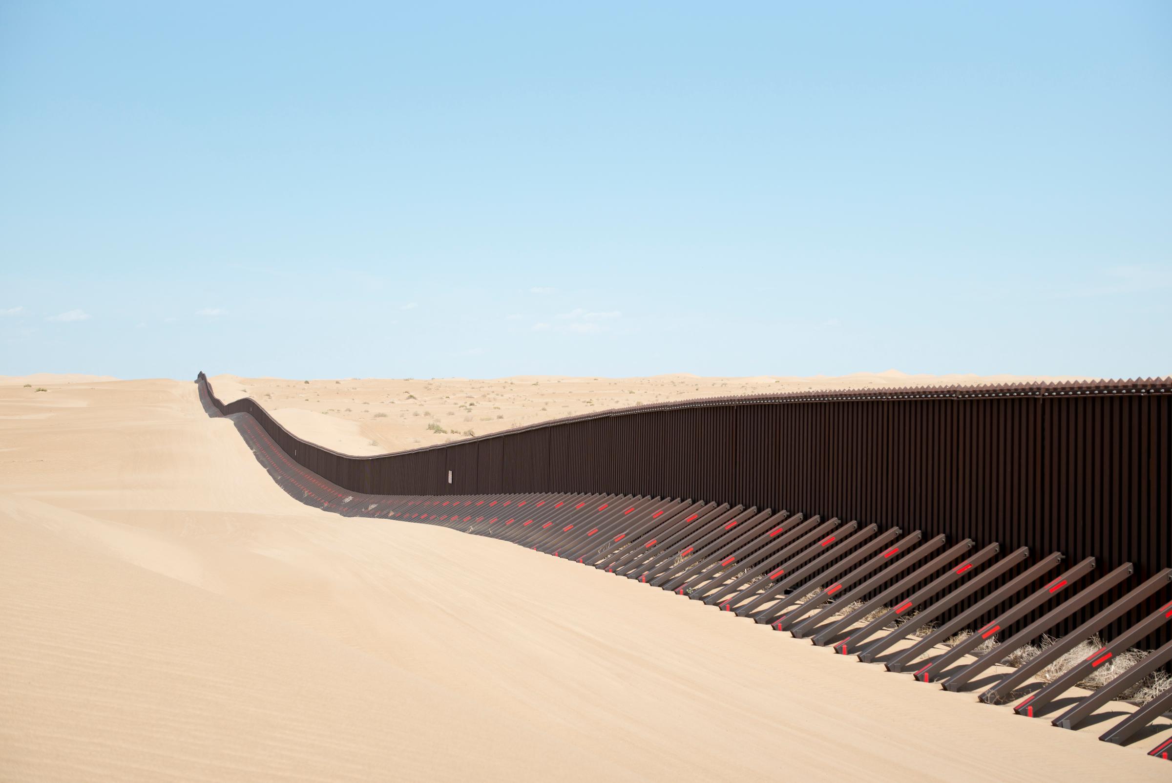 A section of the controversial US-Mexico border fence expansion project crosses previously pristine desert sands at sunrise on May 24, 2014 between Yuma, Arizona and Calexico, California.