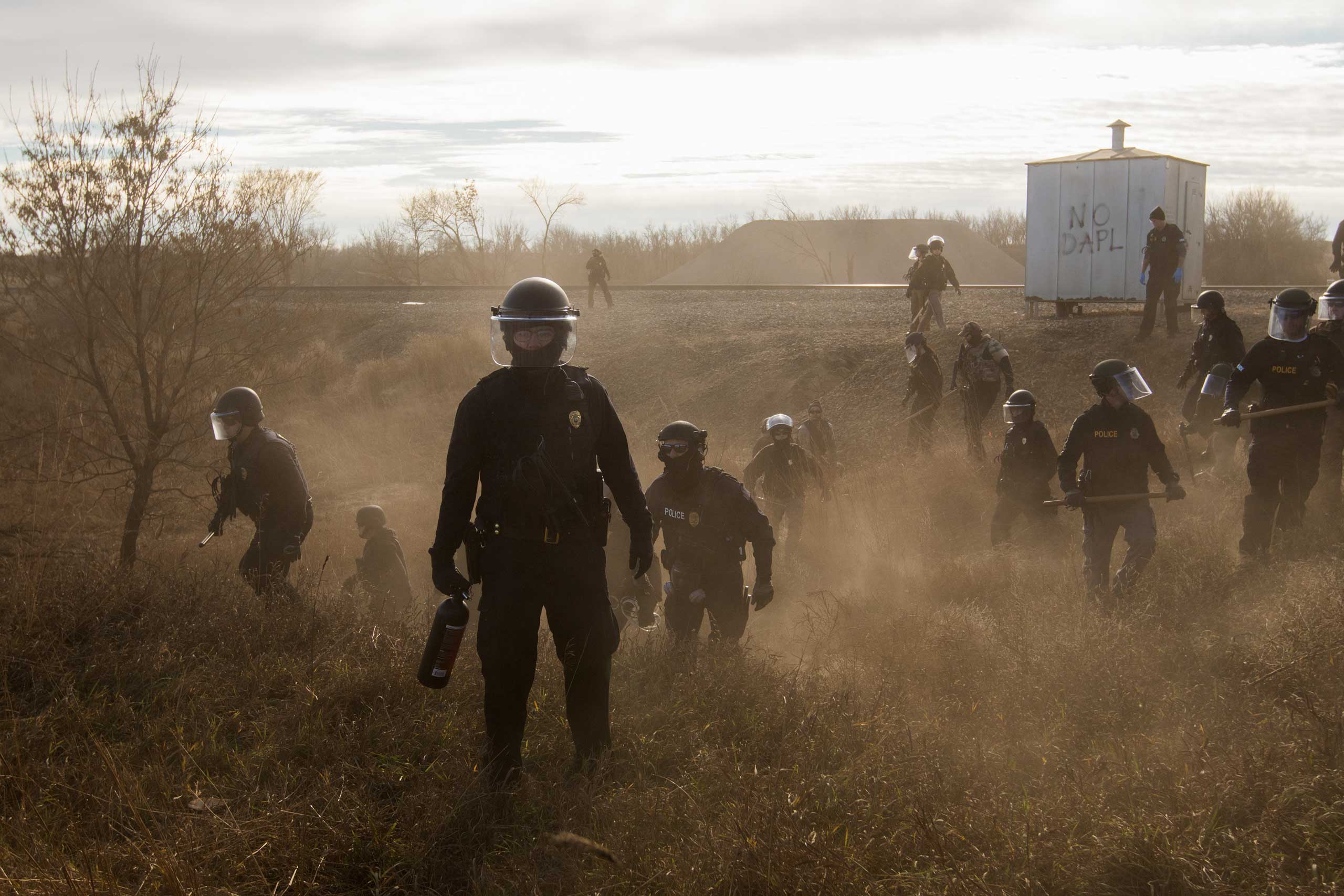 Morton County Sheriffs - Riot police clear marchers from a secondary road outside a Dakota Access Pipeline (DAPL) worker camp using rubber bullets, pepper spray, tasers and arrests. In other incidents they've employed militarized vehicles, water canons, tear gas and have been accused of using percussion grenades.