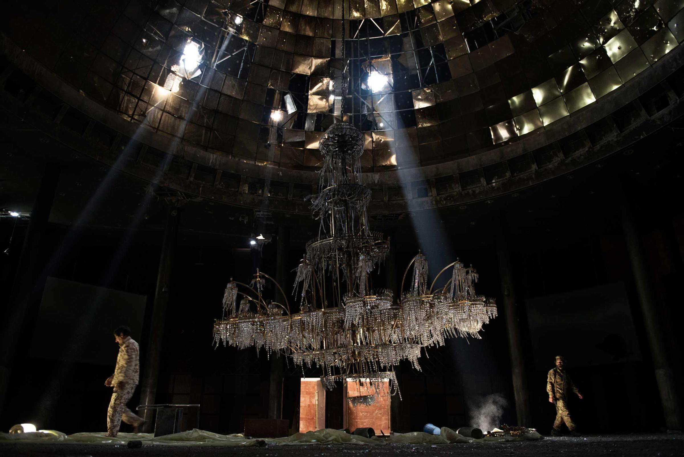 Libya, Sirte: Fighters of the Libyan forces affiliated to the Tripoli government walk around the gigantic chandelier of the conference room in Ouagadougou congress complex on July 14, 2016. Alessio Romenzi