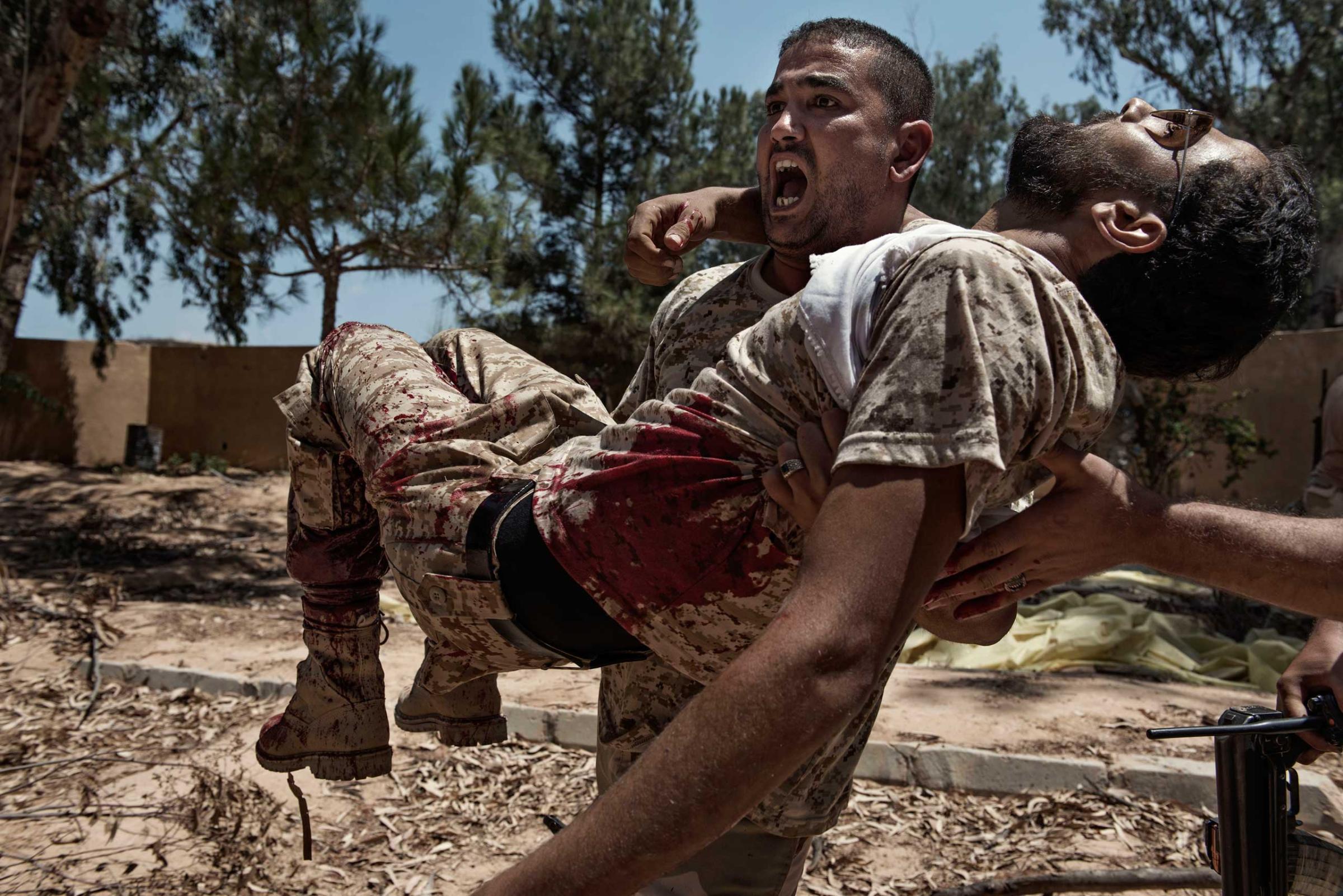 Libya, Sirte: A fighter of the Libyan forces affiliated to the Tripoli government carries a comrade who was seriously injured just seconds before by a booby trap placed by ISIS fighters on July 14, 2016. Alessio Romenzi