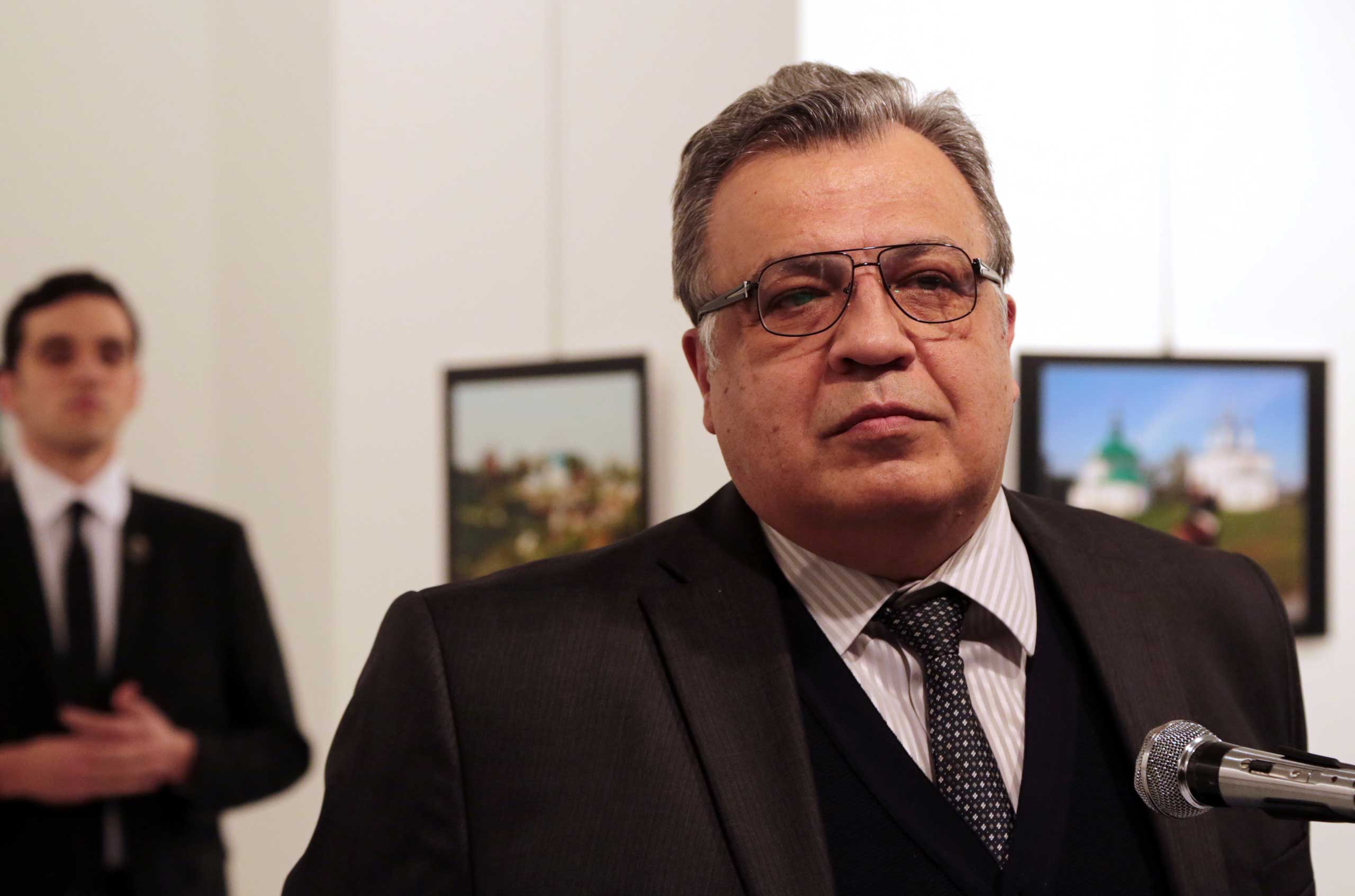 Andrey Karlov, the Russian ambassador to Turkey, speaks at an art gallery before being shot by Mevlüt Mert Altıntaş, left, in Ankara, Turkey.