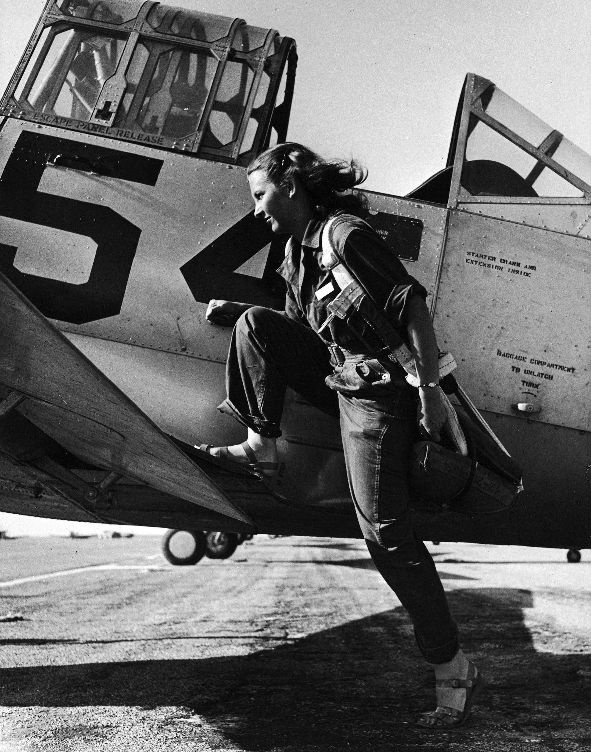 Female pilot of the US Women's Air Force Service posed with her leg up on the wing of an airplane, 1943.