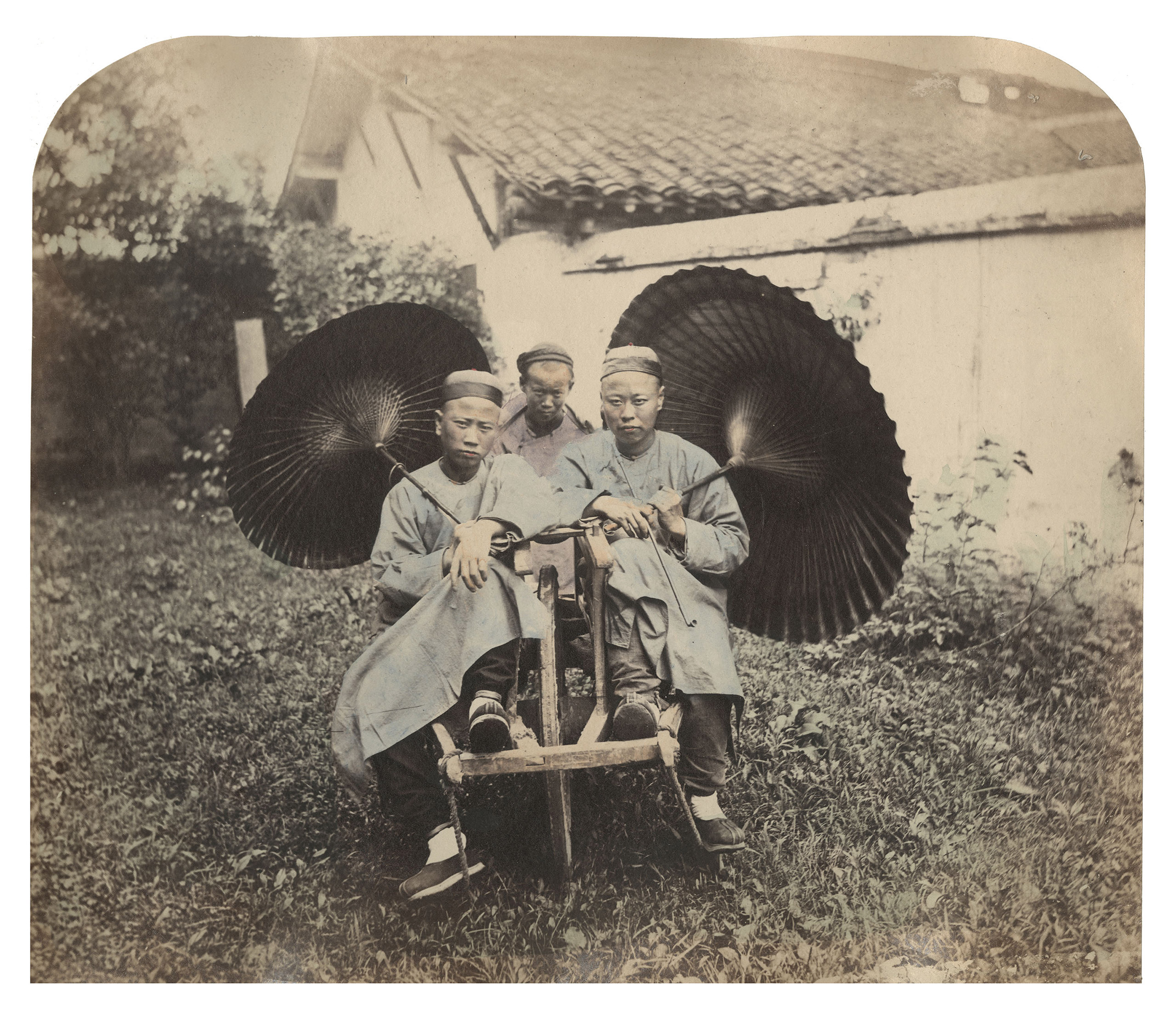 Caption from Stephan Lowentheil Collection. William Saunders was fascinated by traditional Chinese technologies that he believed predated similar inventions in the West. In this photograph, two men pose on a man-powered vehicle – a wheelbarrow typical of late Qing Shanghai. The driver stands at the rear. Their assertive gazes suggest a confidence before the camera that was unusual in late Qing Dynasty photographs.