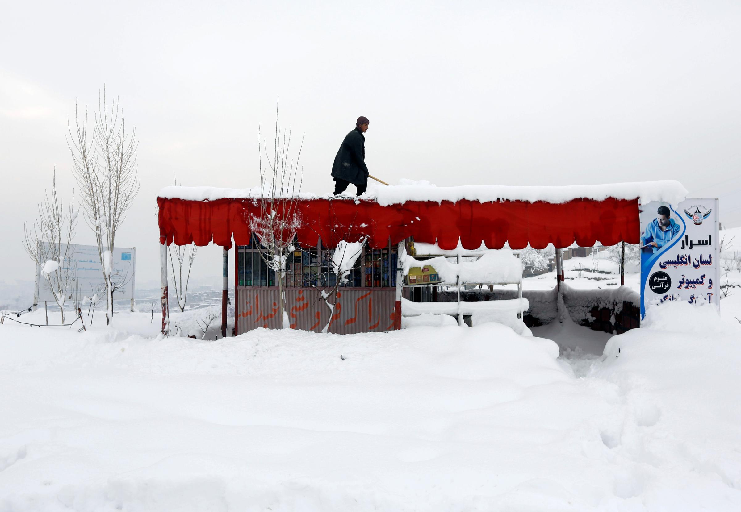 An Afghan man removes snow from his shop on the outskirts of Kabul, Afghanistan February 5, 2017.REUTERS/Omar Sobhani - RTX2ZO84