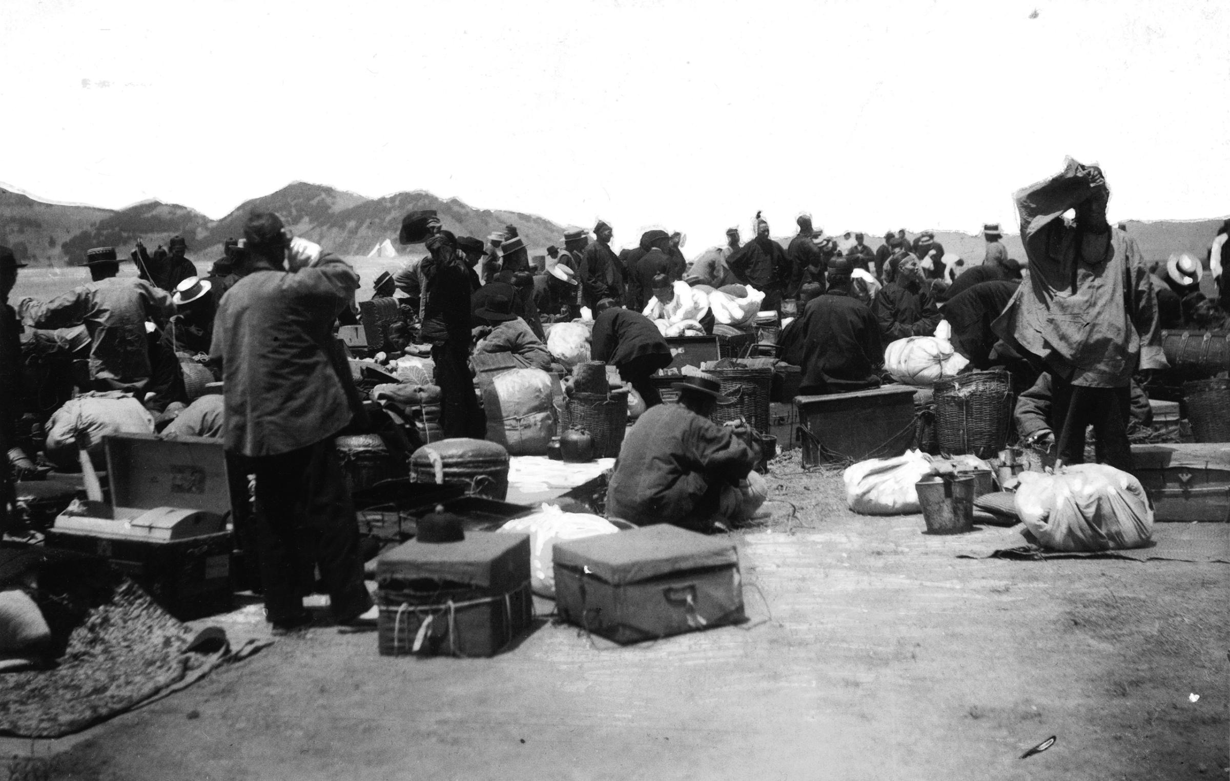 A group of Chinese and East Asian immigrants wait on a wharf after disinfection at Angel Island, San Francisco Bay, California, ca. 1910s.