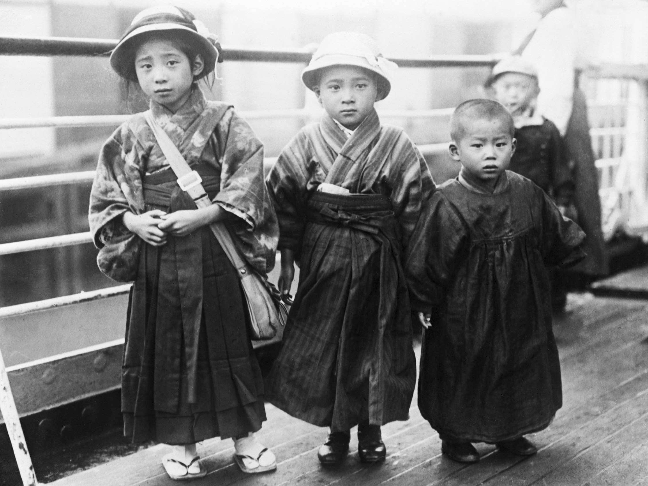 Three Japanese children stand on the deck of the Shinyo Maru as it arrives in San Francisco, ca. 1920.