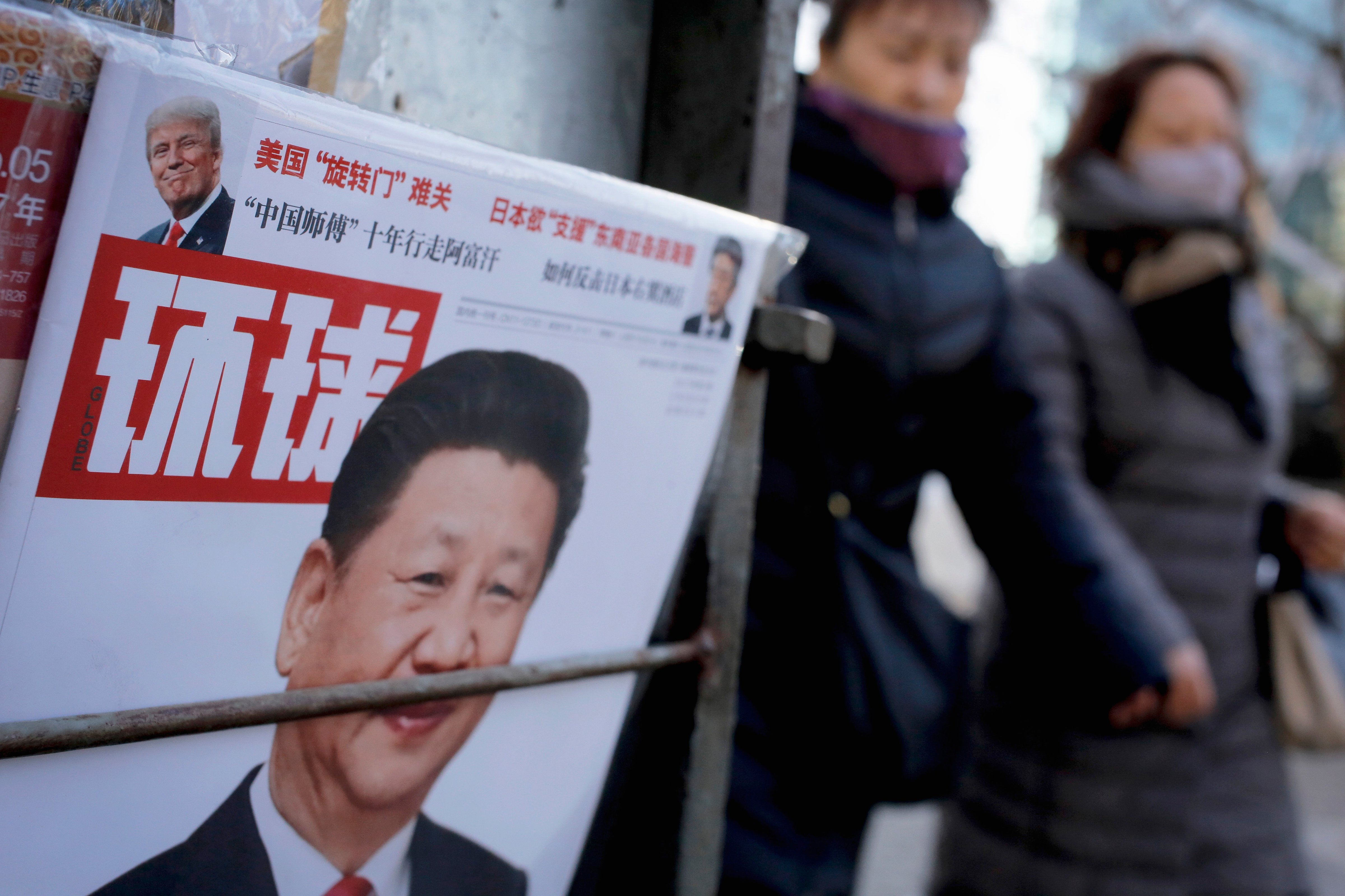 Women walk past a newsstand displaying a Chinese news magazine fronting a photo of Chinese President Xi Jinping and that of U.S. President Donald Trump in Beijing on Feb. 9, 2017 (Andy Wong—AP)