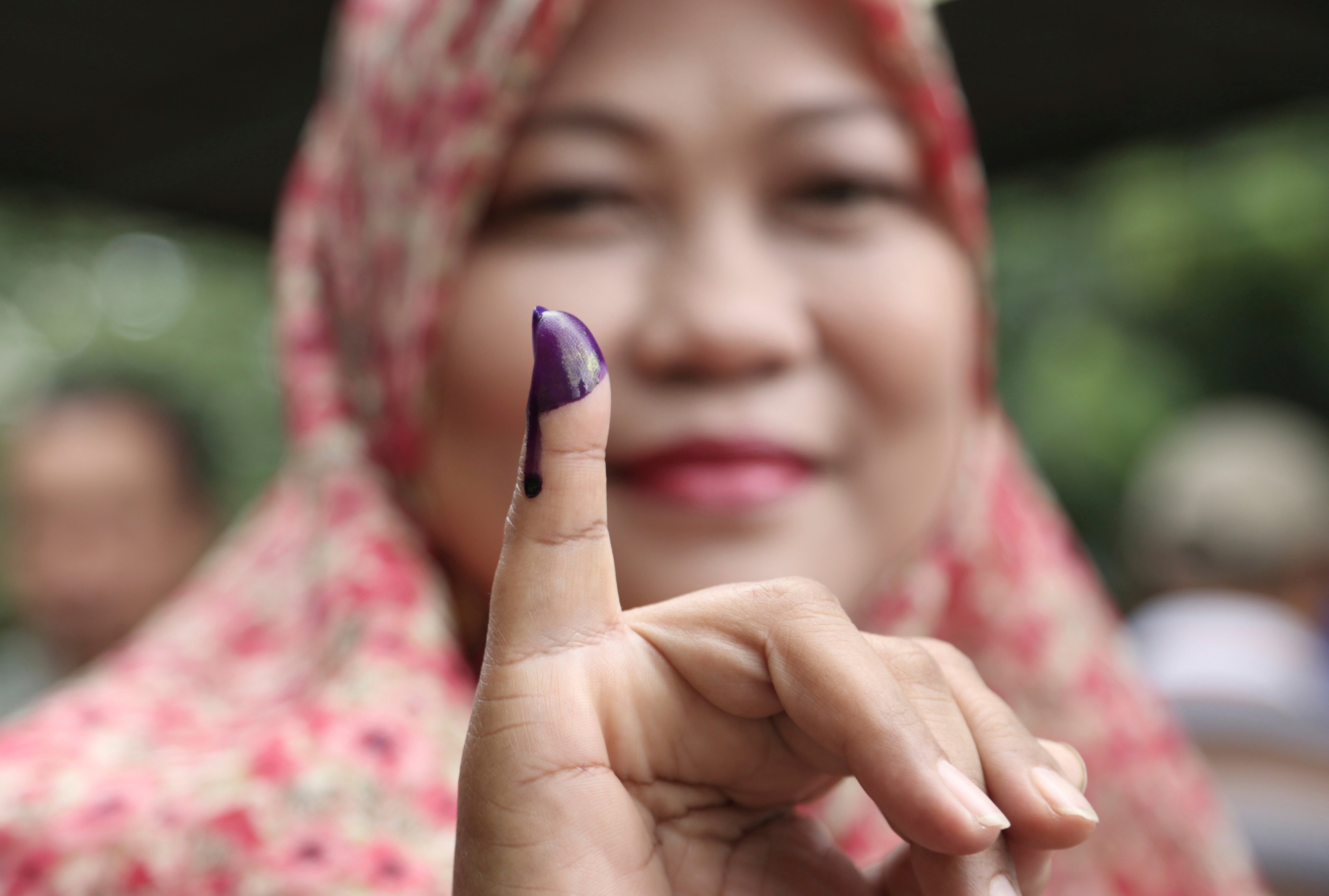A Muslim woman shows her ink-stained finger after voting in the gubernatorial election in Jakarta on Feb. 15, 2017 (Achmad Ibrahim—AP)