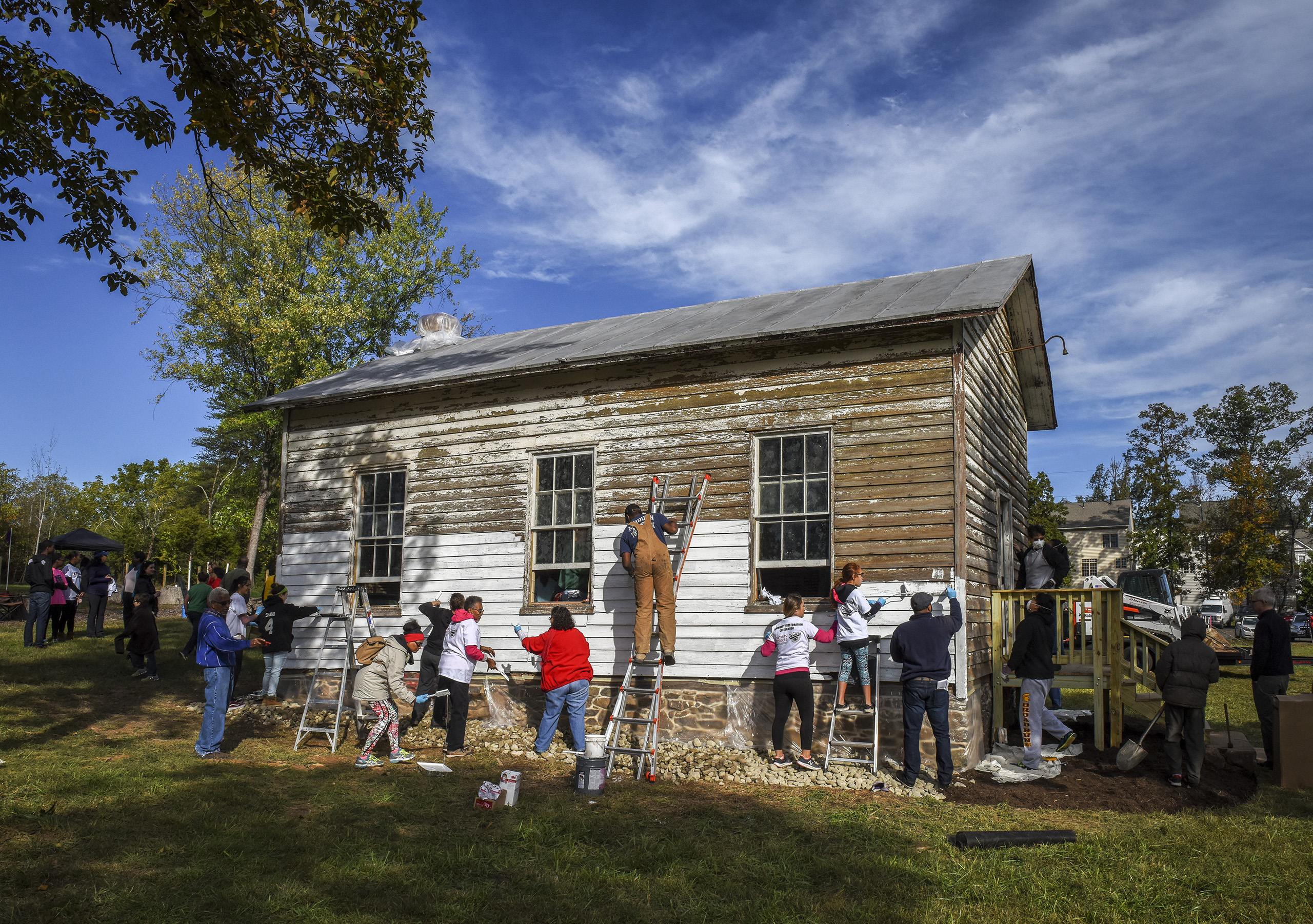 A group tackles painting the exterior as volunteers gather to restore the Ashburn Colored School, a nineteenth-century schoolhouse vandalized with racist symbols and hate language,  in Ashburn, VA on Oct. 9, 2016. (Bill O'Leary—The Washington Post/Getty Images)