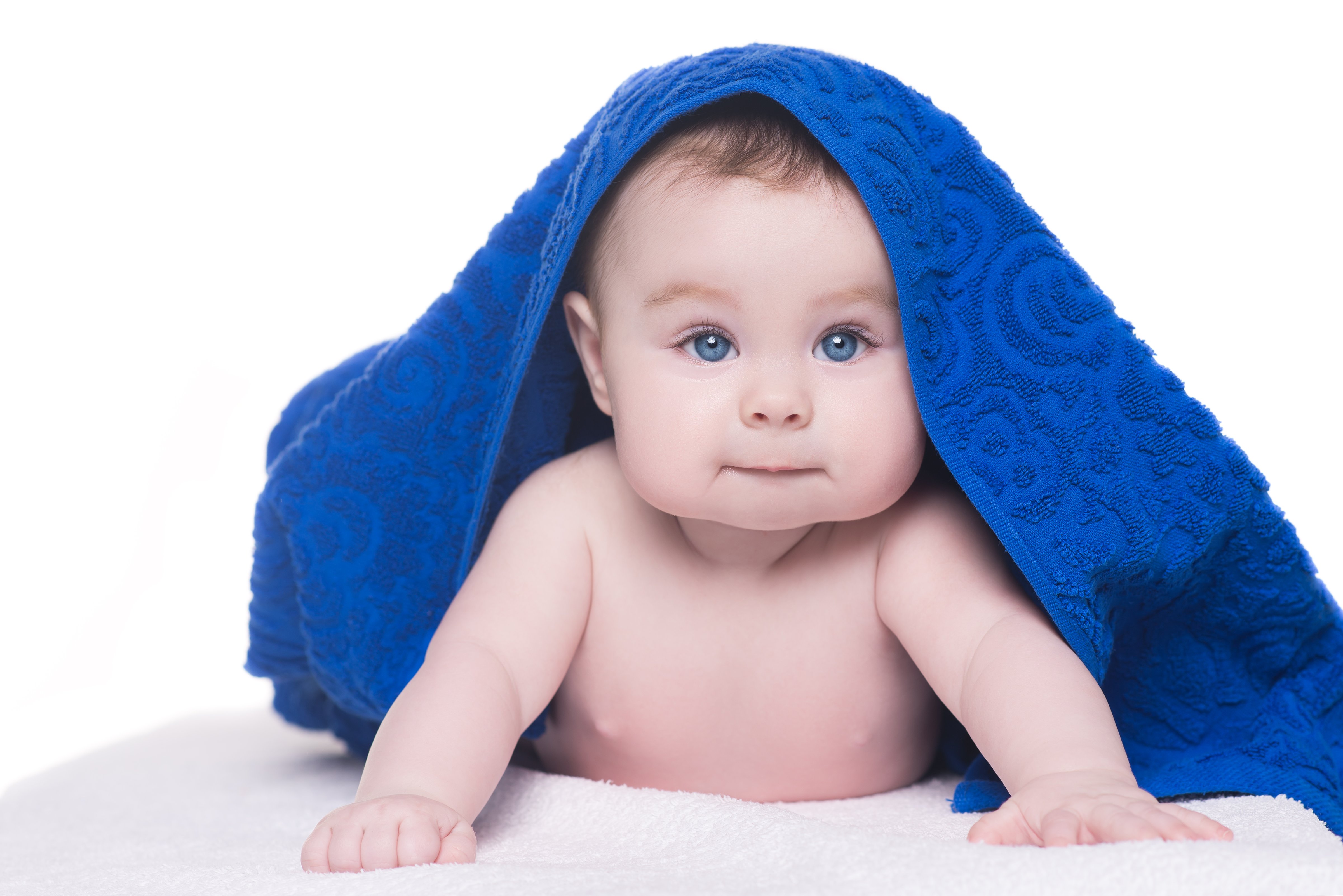 baby with big blue eyes looking at camera under blue towel/blanket. child tries to crawl on his belly with blue eyes under a blue towel on head. kid looks into camera (Irina Lapeto—Getty Images/iStockphoto)
