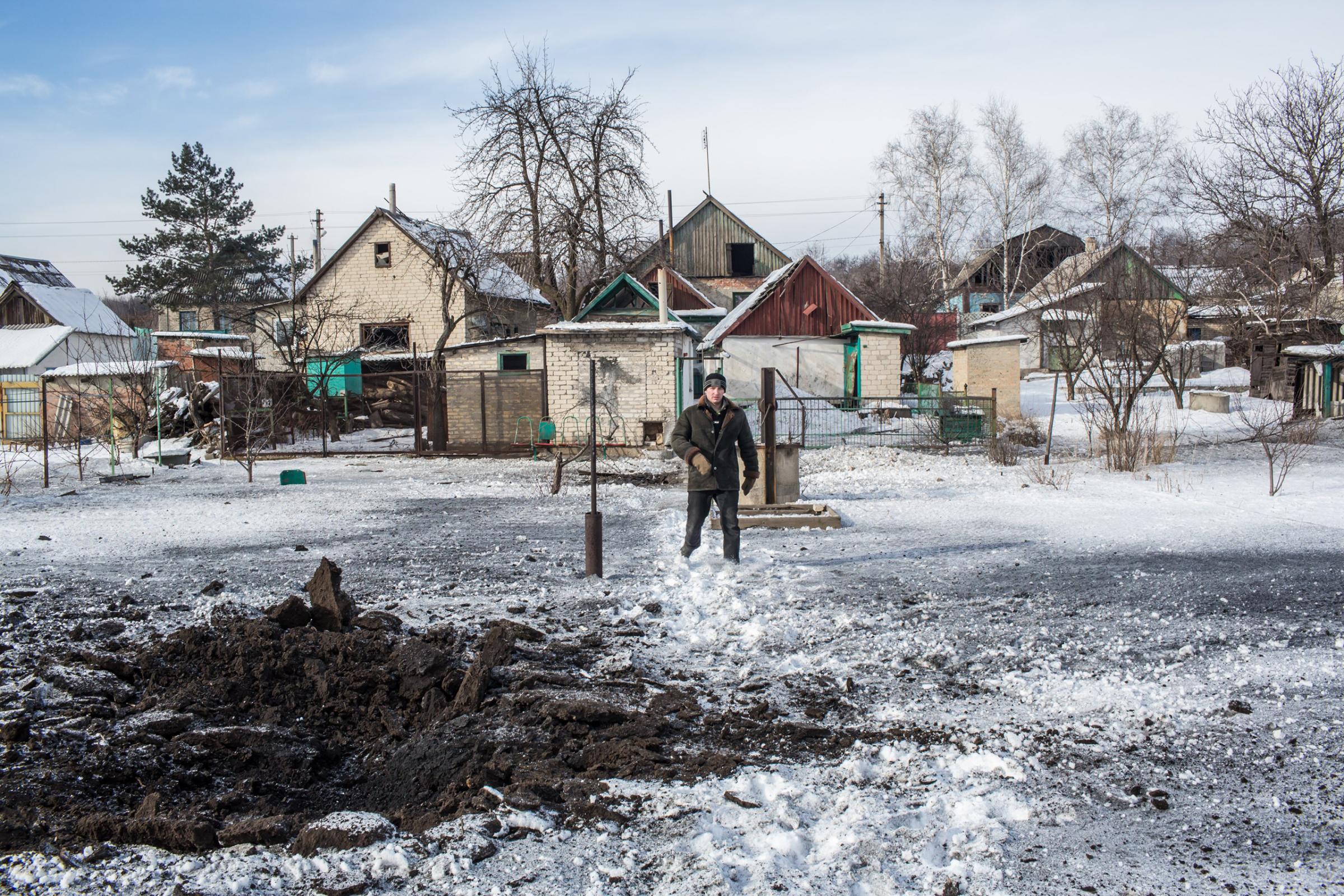 A man shows where one of six grad rockets landed in his backyard in Avdiivka, Ukraine, on Feb. 1, 2017.