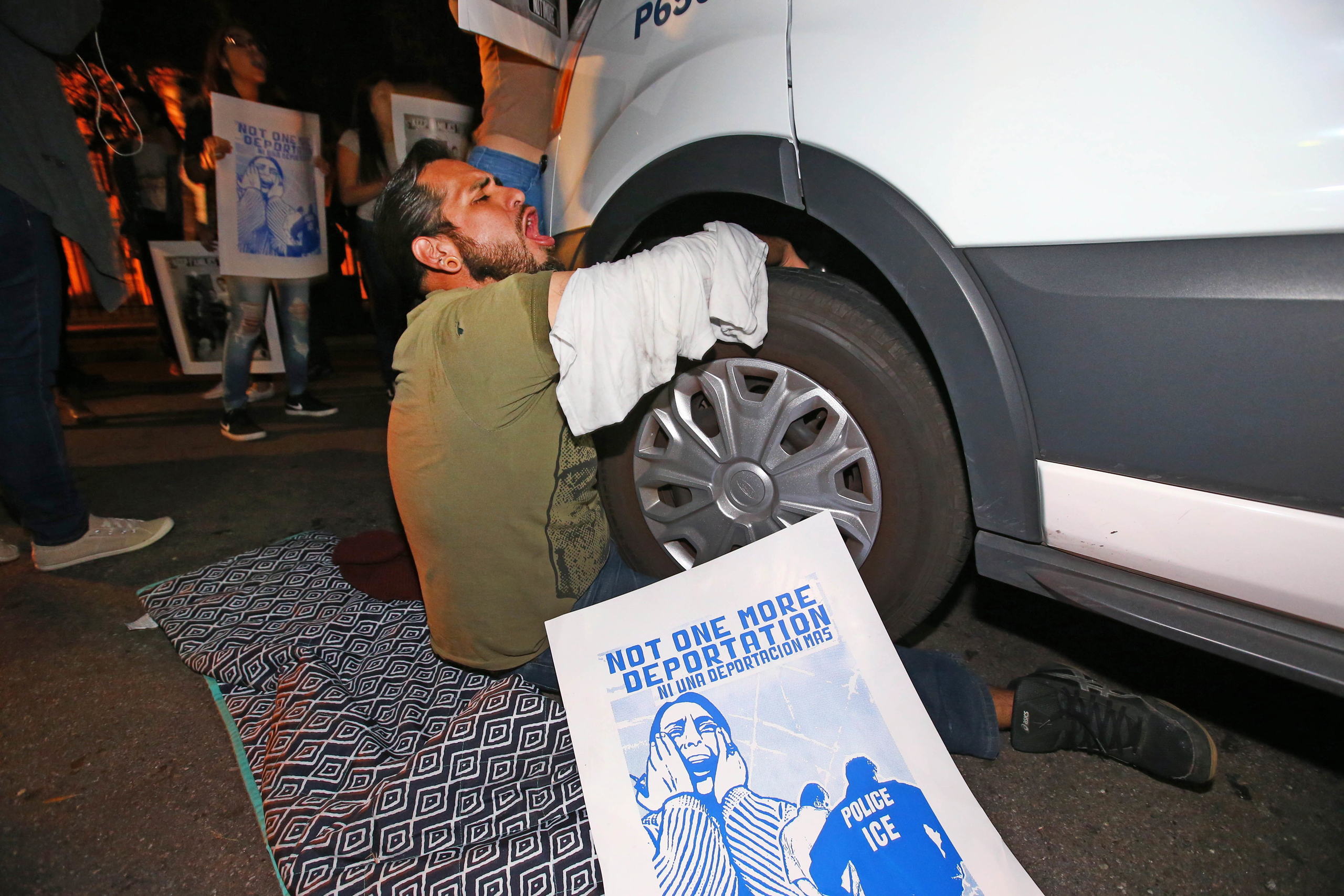 A protester locked himself to the van carrying Guadalupe Garcia de Rayos that is stopped by protesters outside the Immigration and Customs Enforcement facility, in Phoenix on Feb. 8, 2017. (Rob Schumacher—The Arizona Republic/AP)