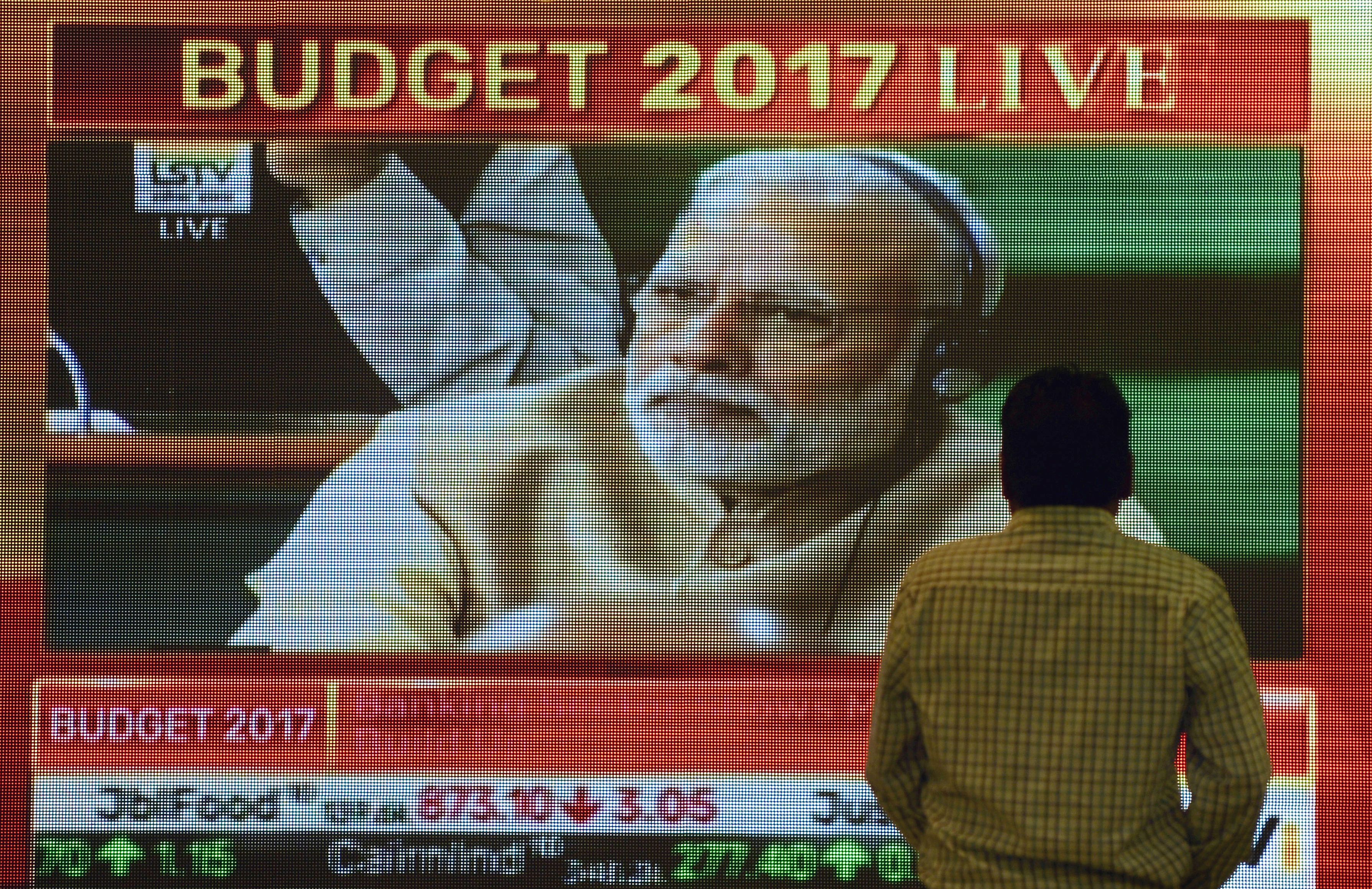 A bystander at the Bombay Stock Exchange walks past a screen showing Indian Prime Minister Narendra Modi listening to Finance Minister Arun Jaitley's delivery of the budget speech at Parliament on Feb. 1, 2017 (Punit Paranjpe—AFP/Getty Images)
