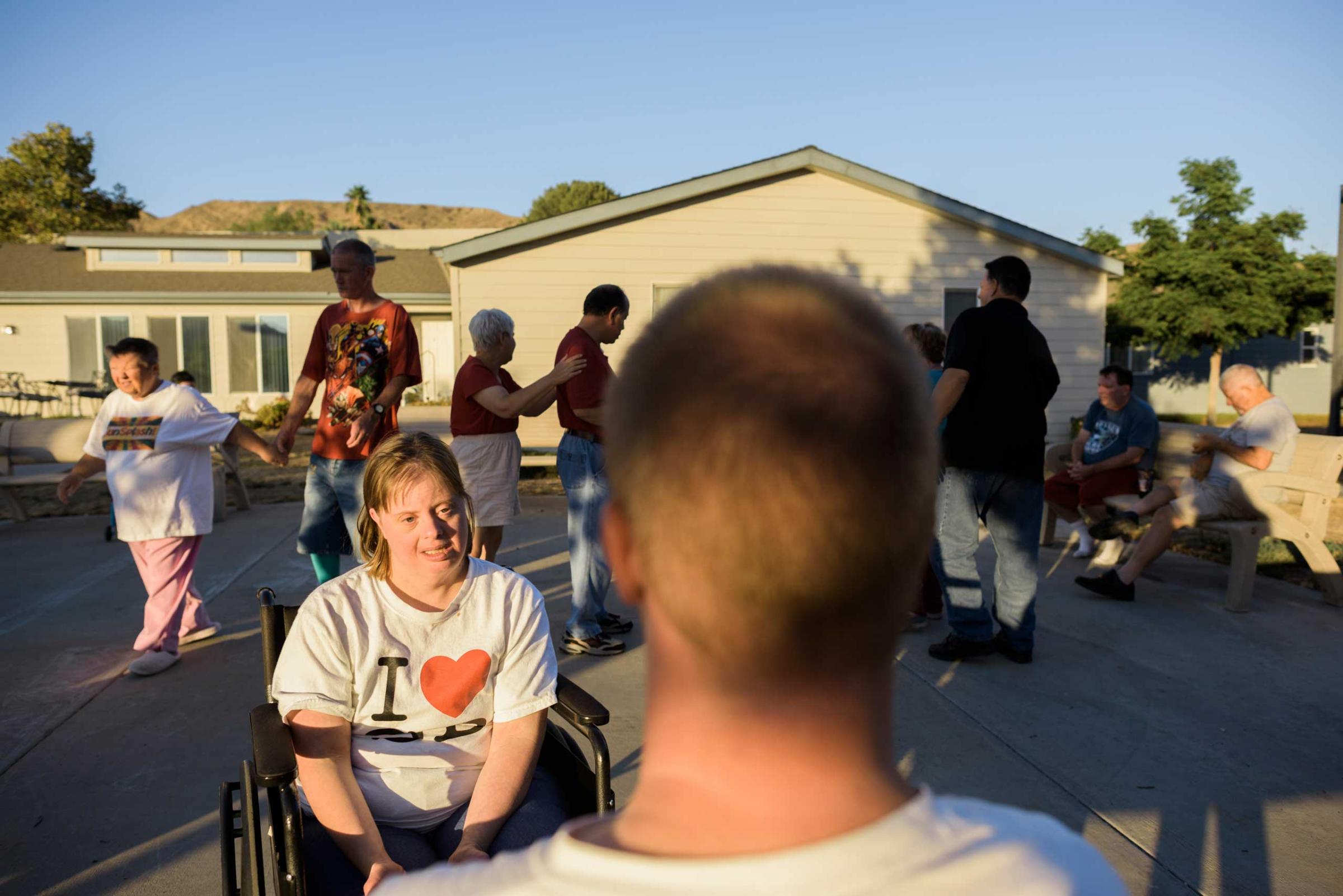 Krysta and Nathaniel sit together in front of their homes during an outside dance party with other community members.