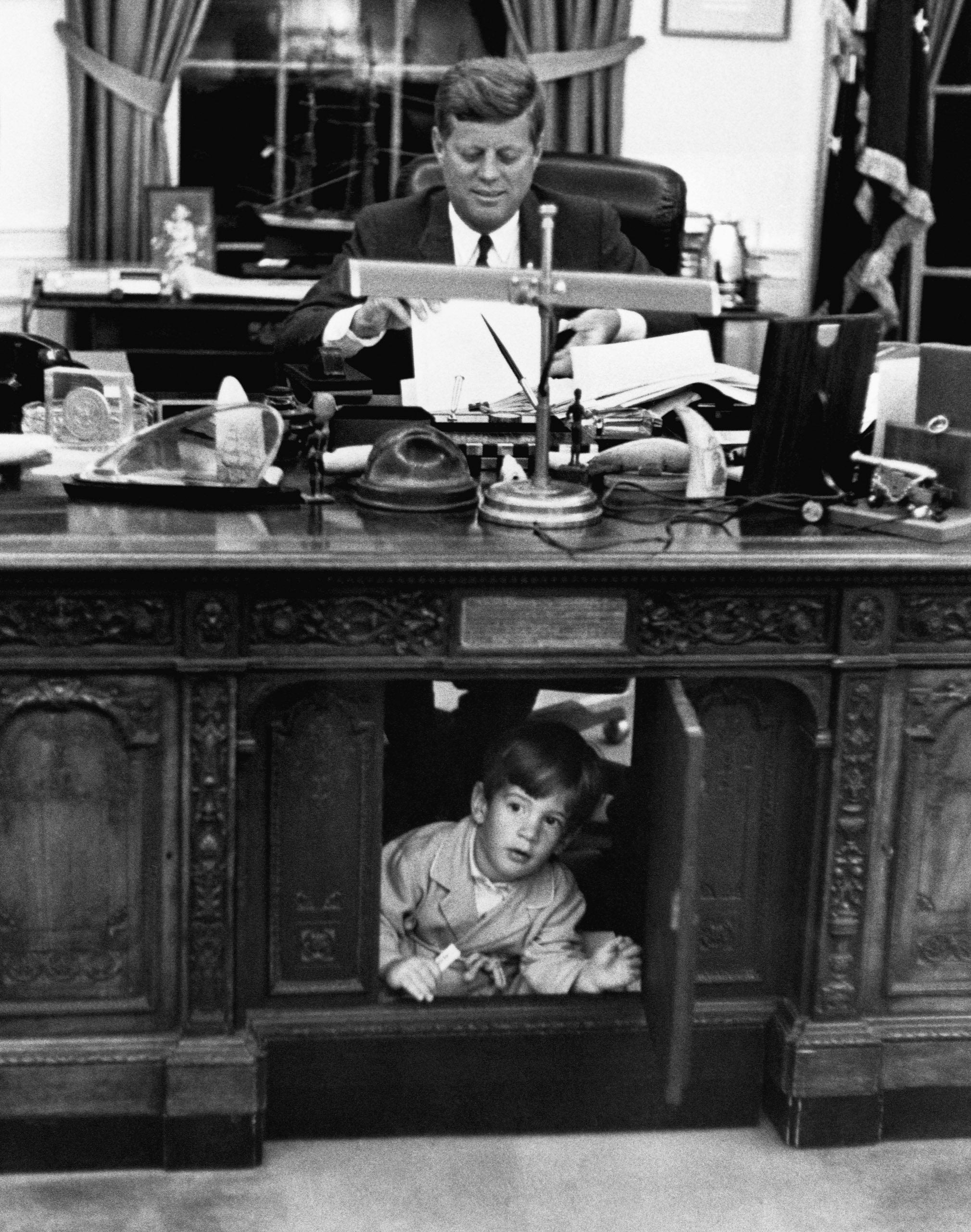 Pres. John F. Kennedy playing w. his son John F. Kennedy Jr. at his desk in the Oval Office. 1963.